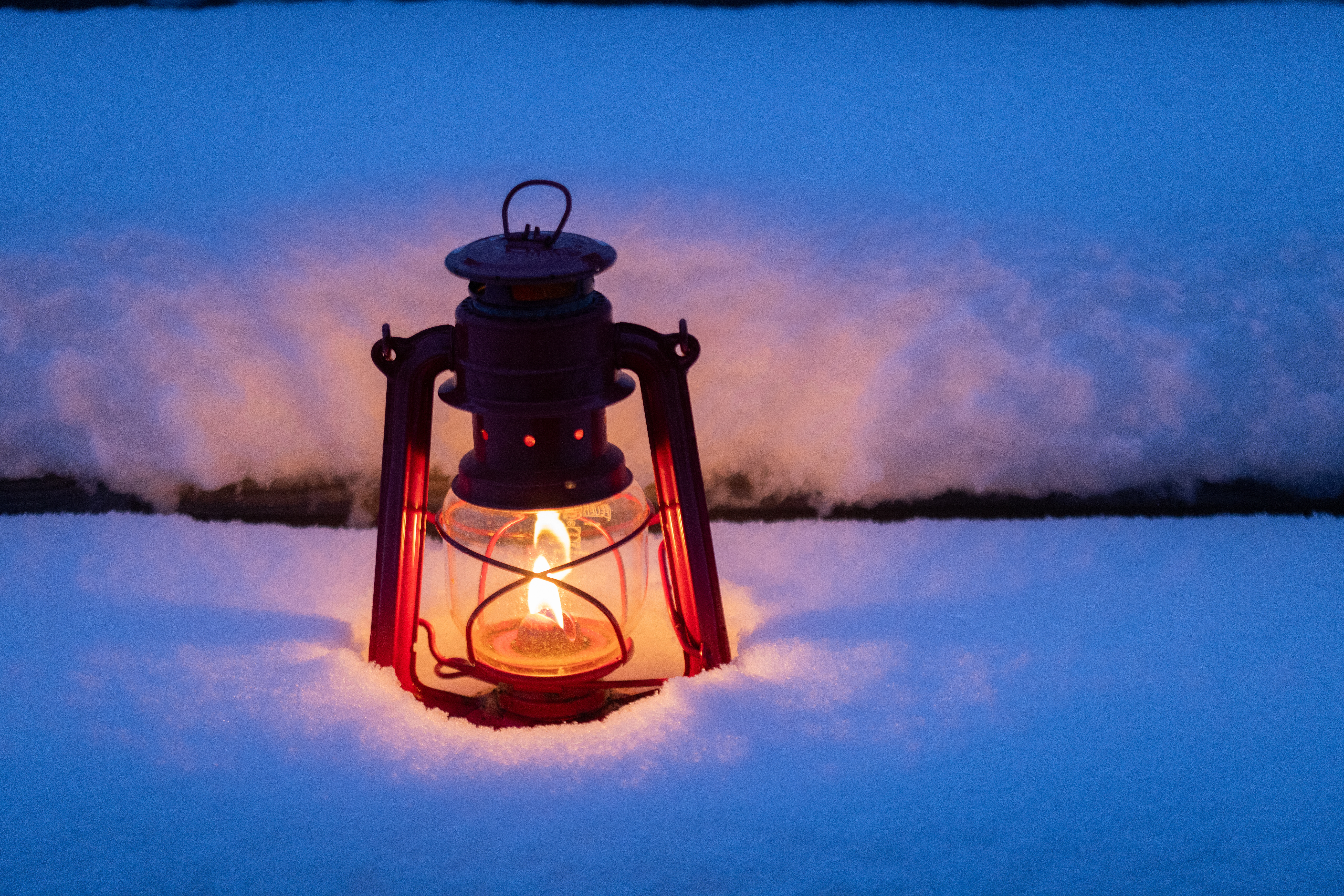 En tänd ljuslykta i snön.