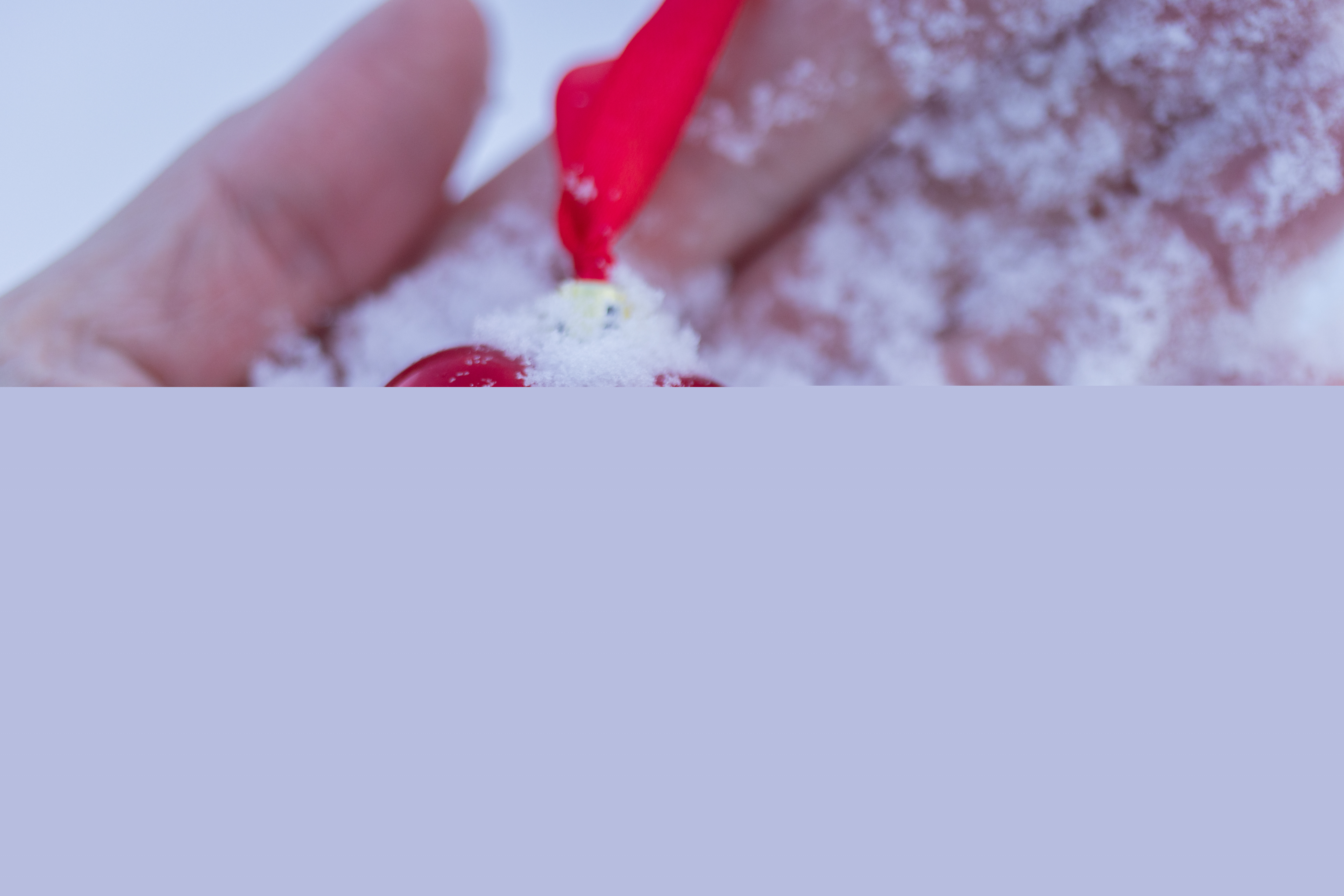 Ett snöigt rött hjärta med siden band ligger i en handflata.