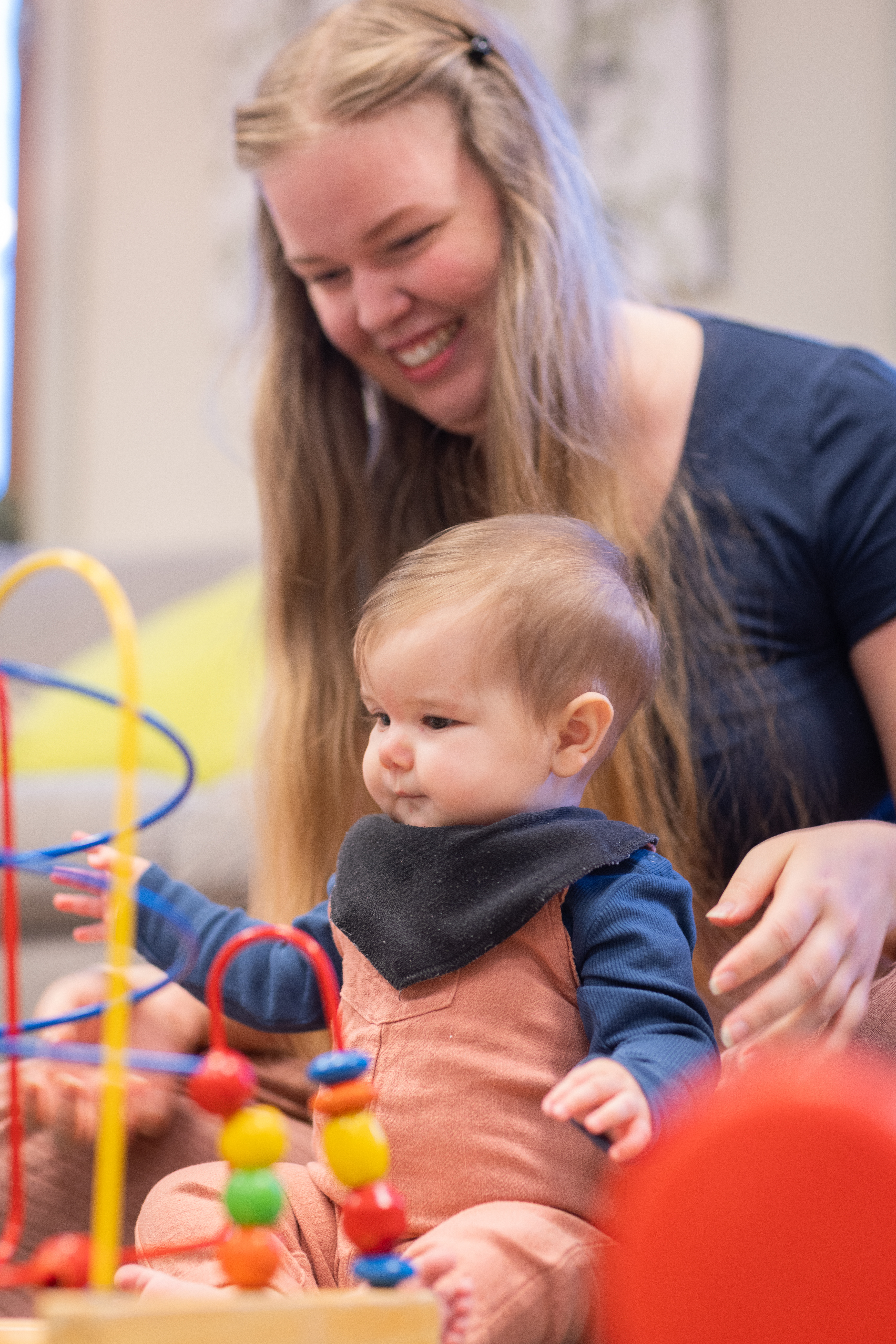 En kvinna sitter på golvet och leker med sin bebis.