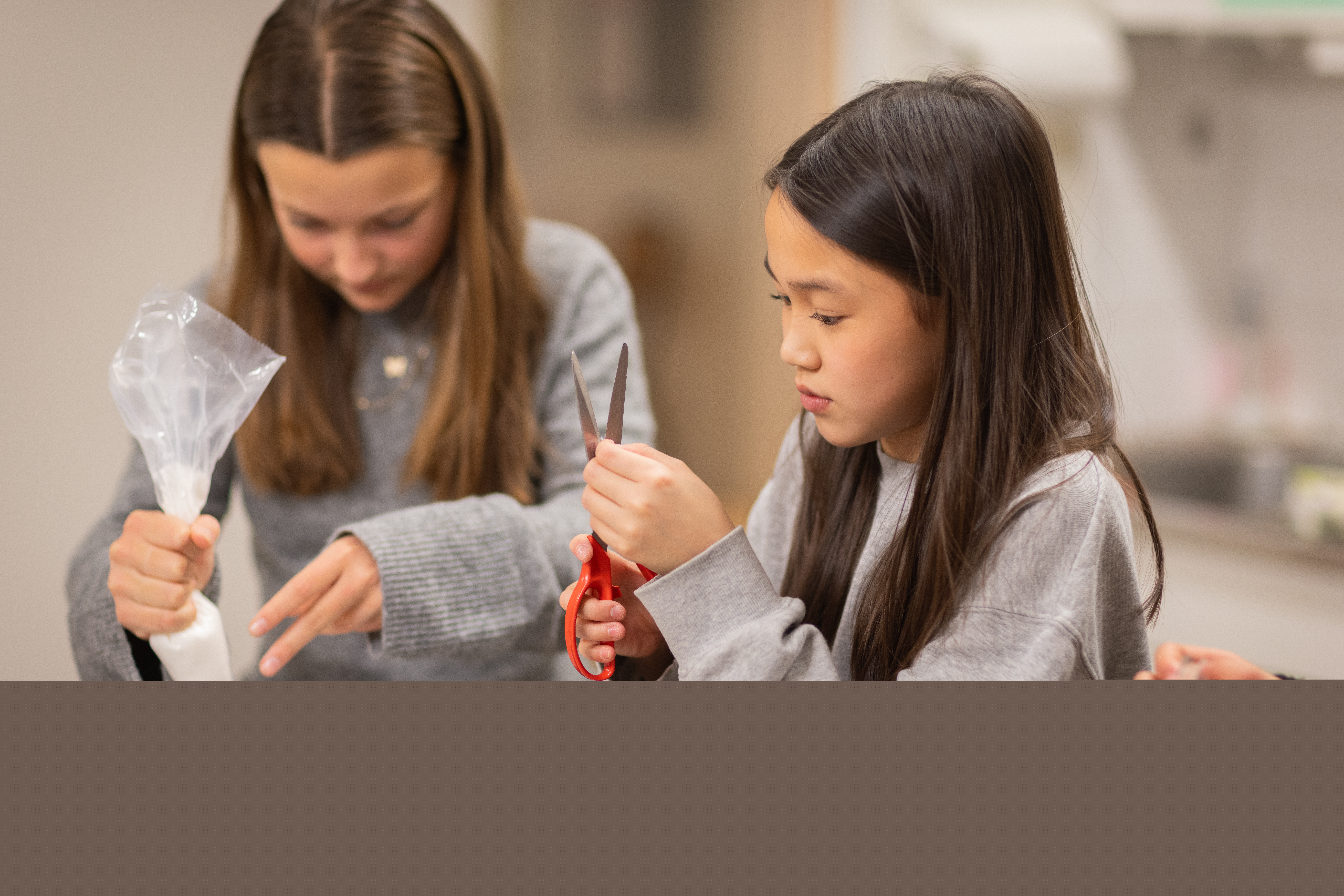 Två flickor pysslar i ett kök.