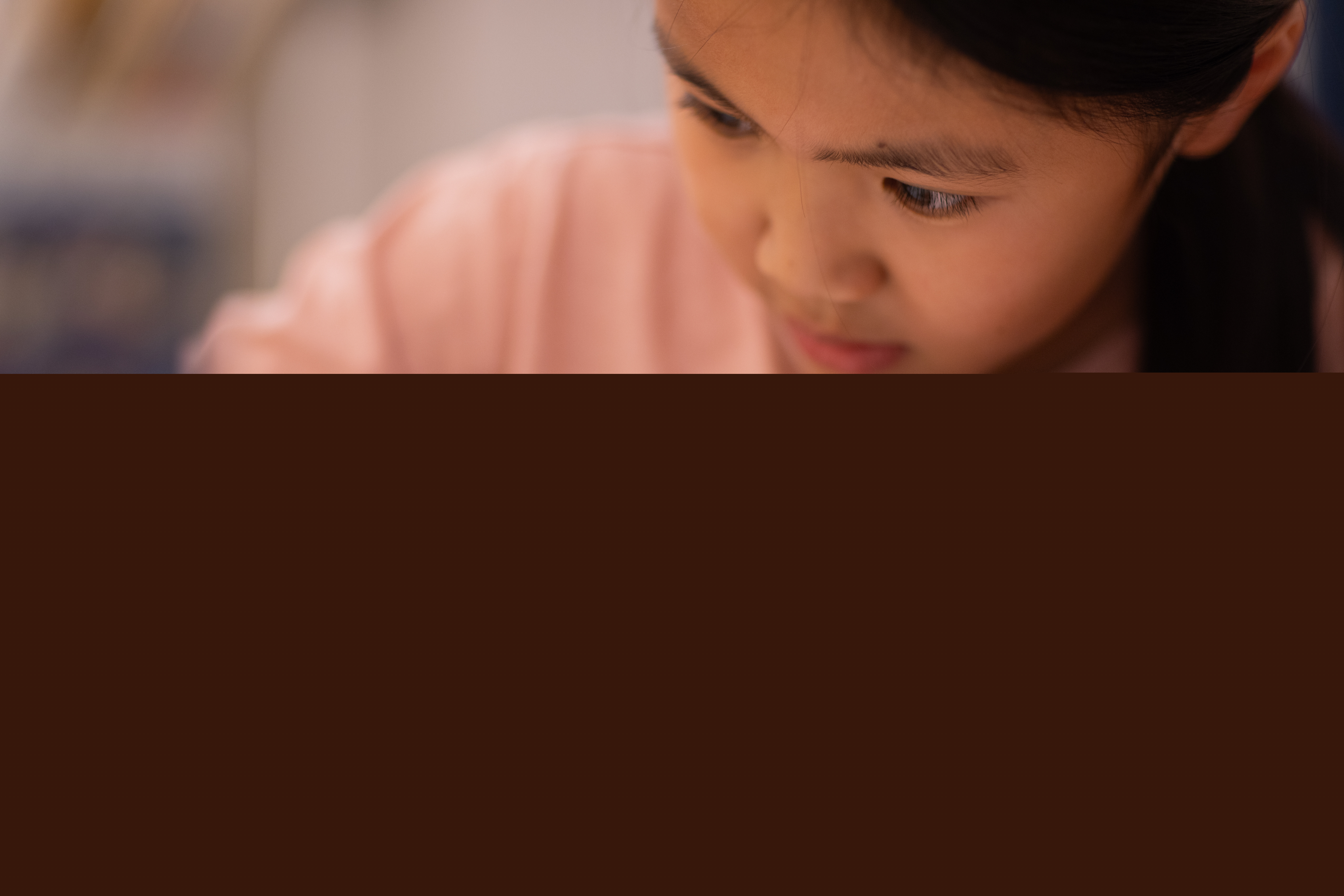 En liten flicka sitter och skriver vid ett bord.