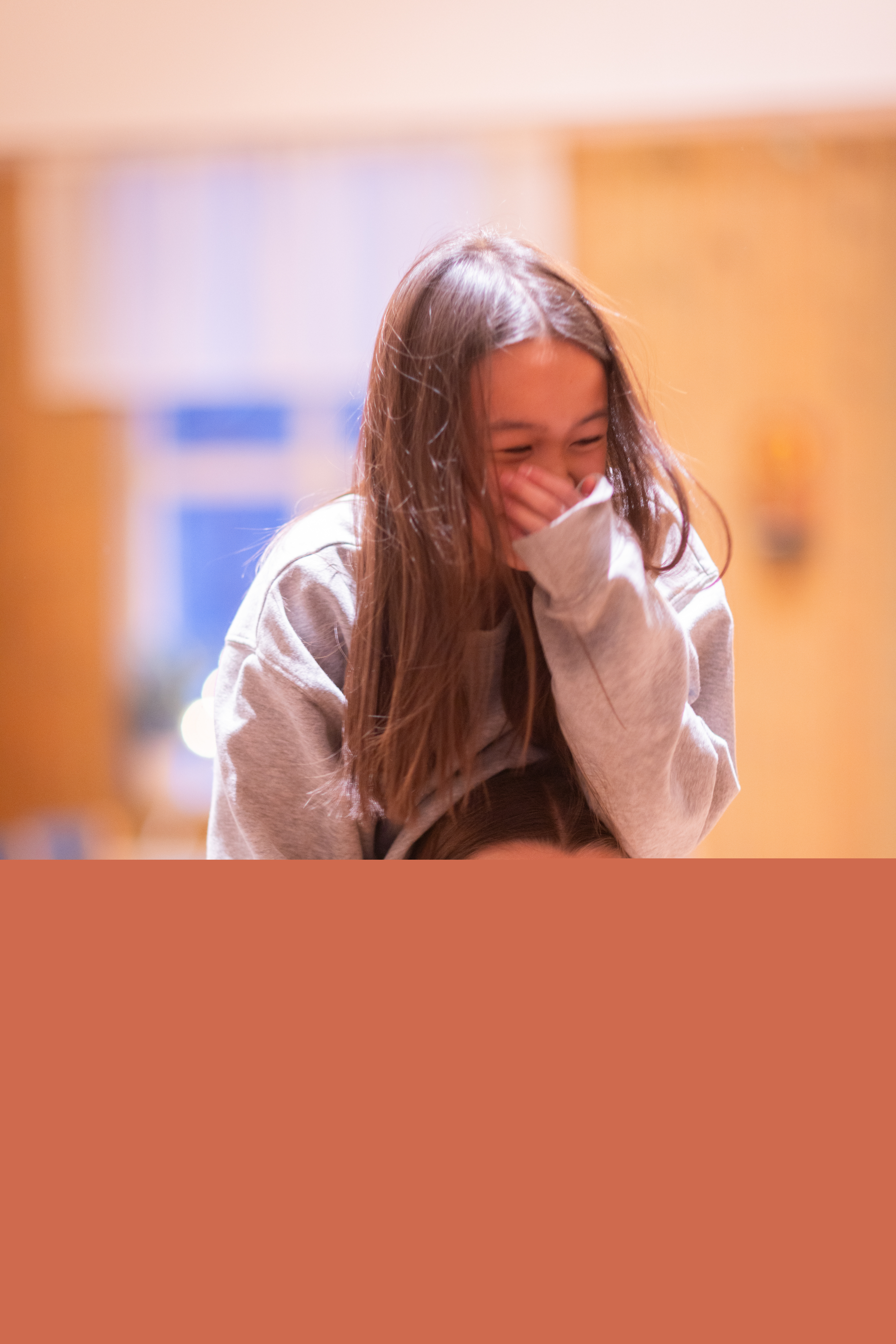 En tjej bär en annan på sina axlar. Båda skrattar.