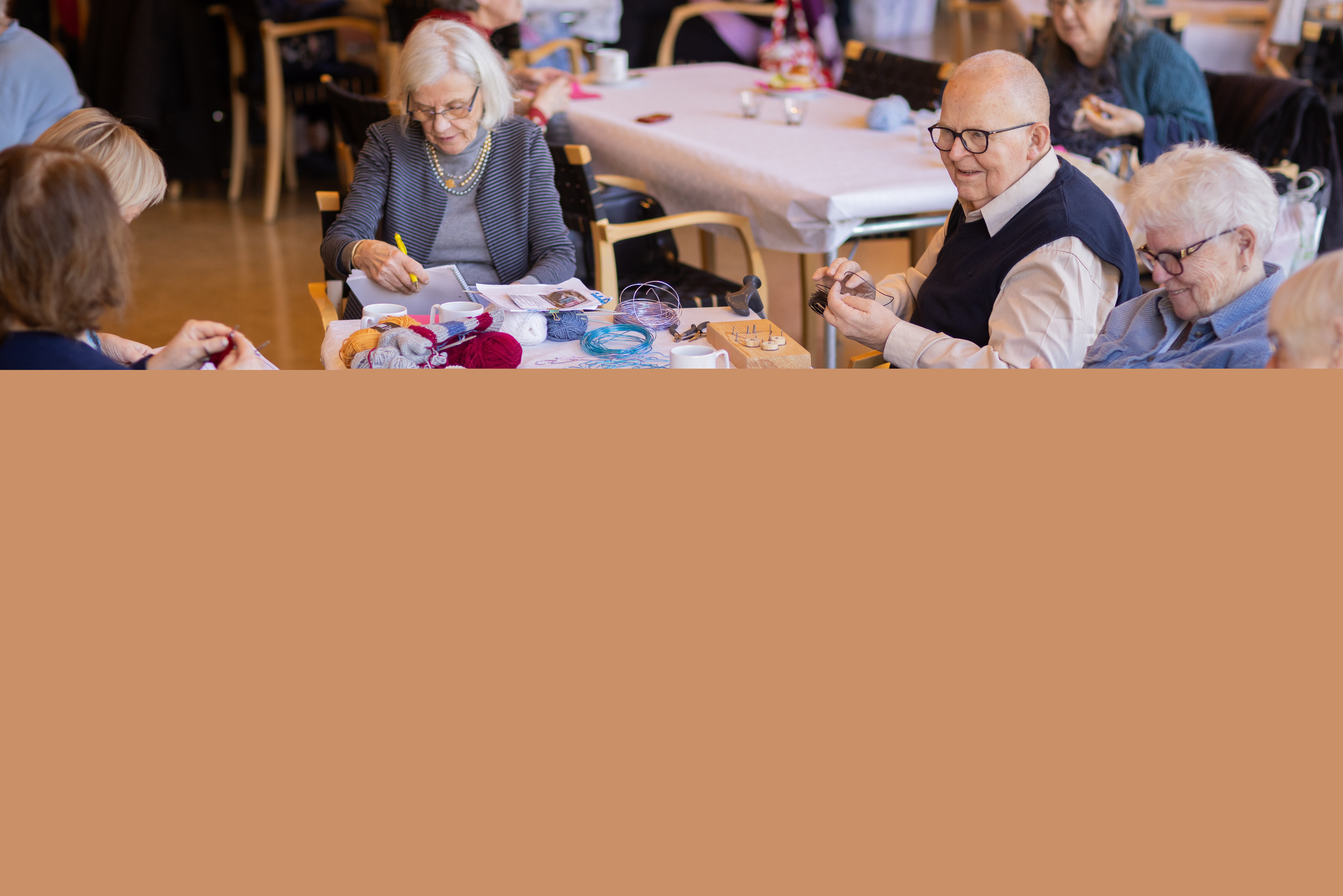 Flera äldre personer sitter vid ett bord och pysslar.