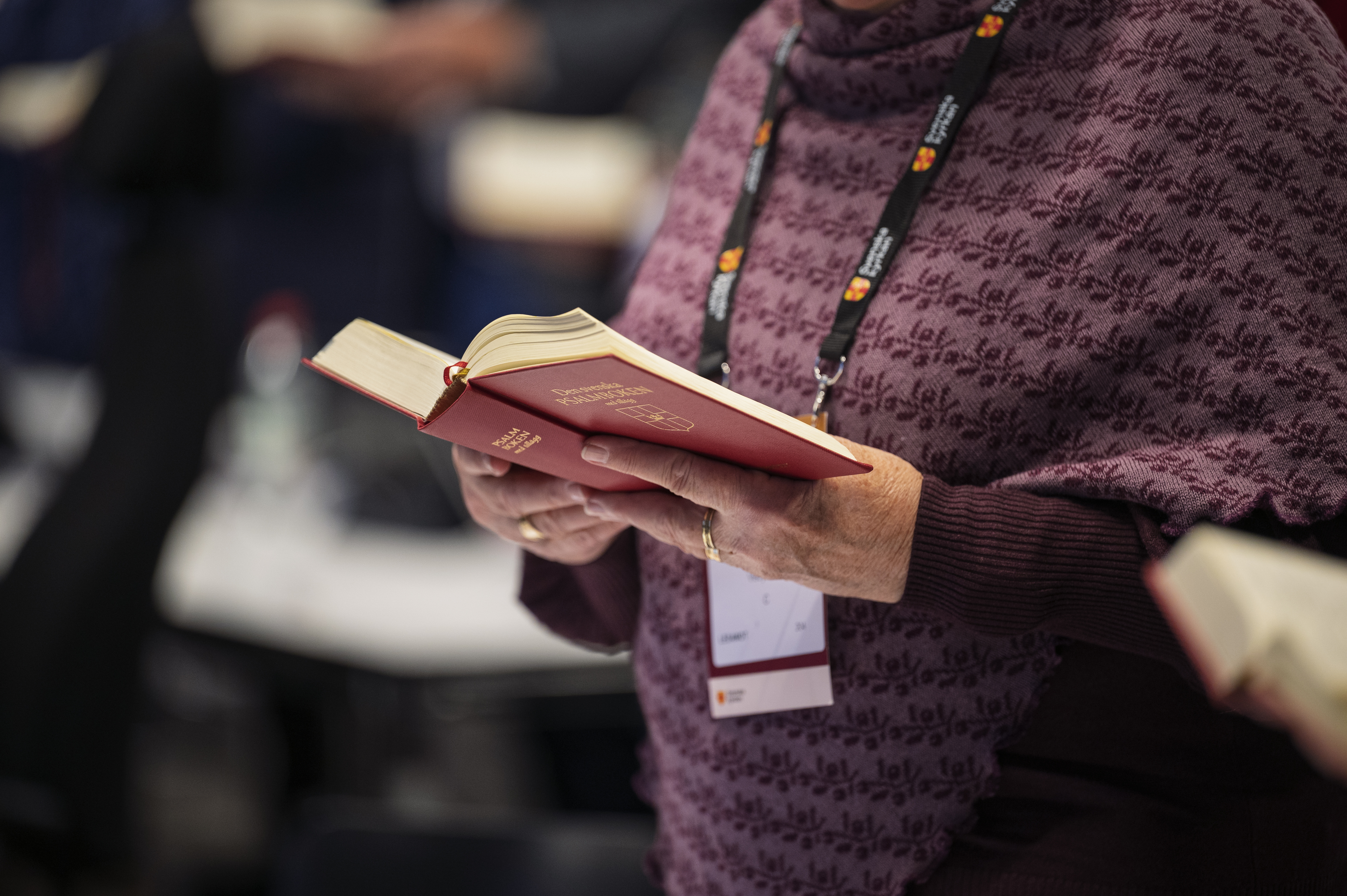 En person står med en uppslagen psalmbok i händerna.