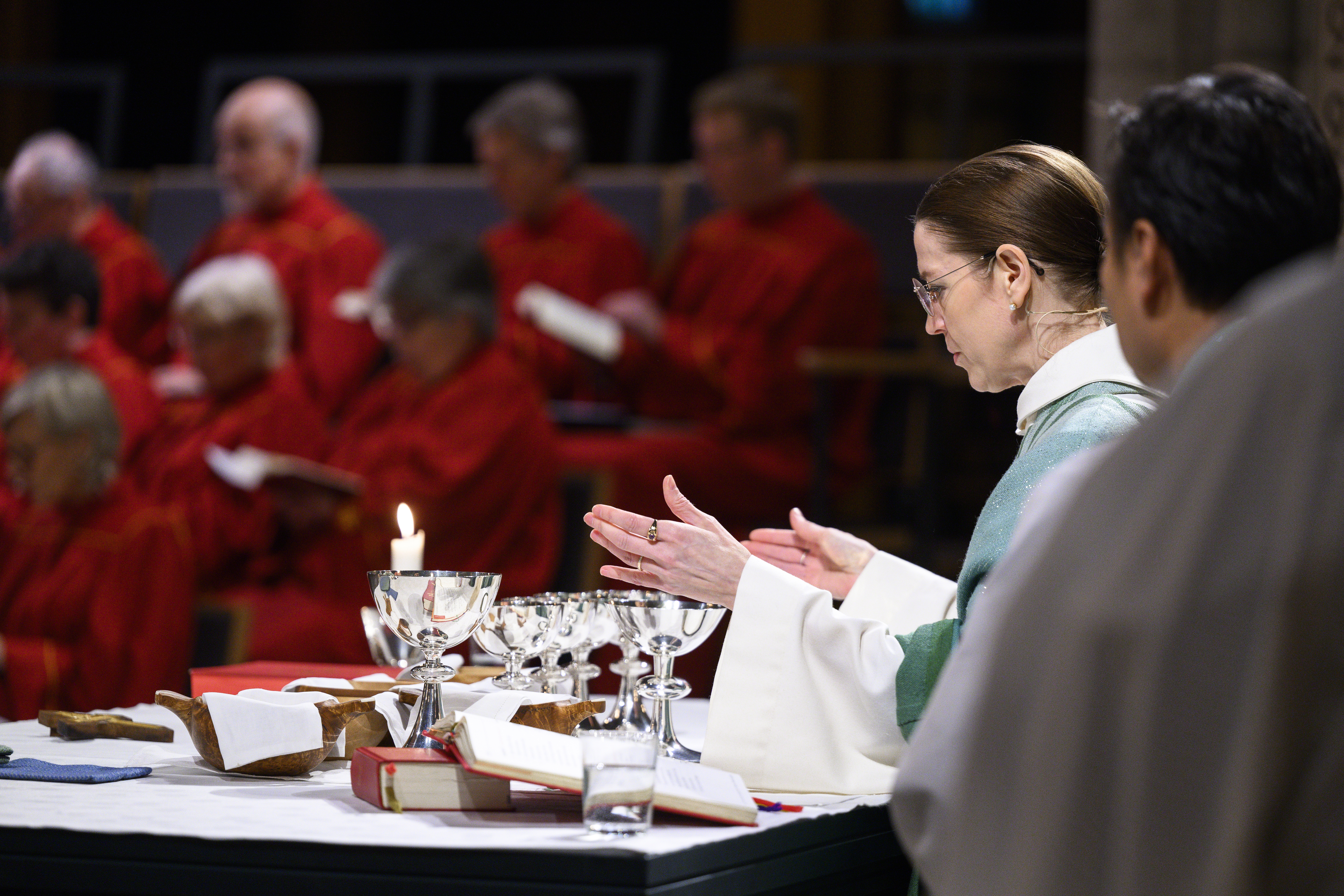 En kvinnlig präst välsignar nattvardens vin och bröd.