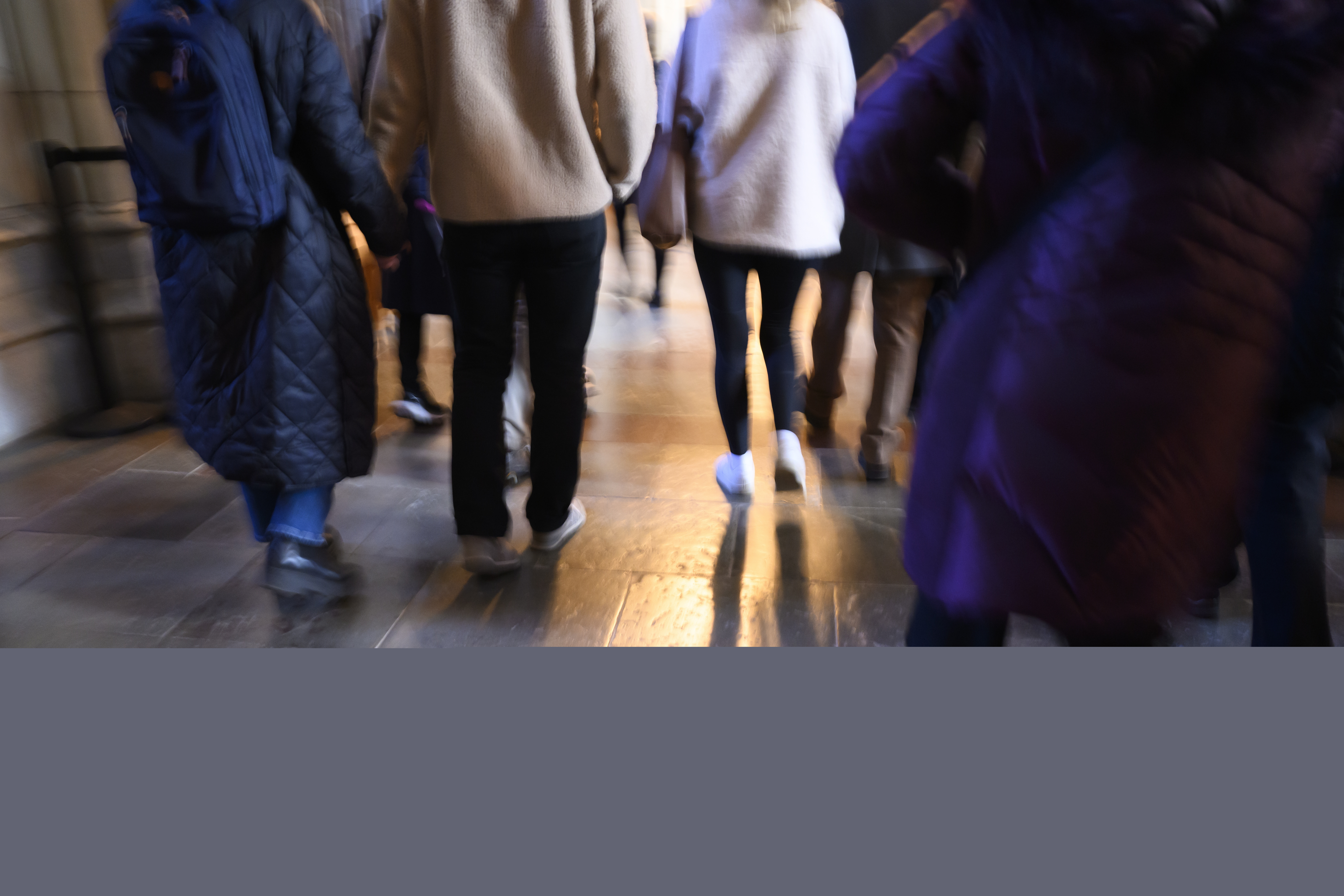 Besökare i en kyrka går med ryggarna mot kameran.