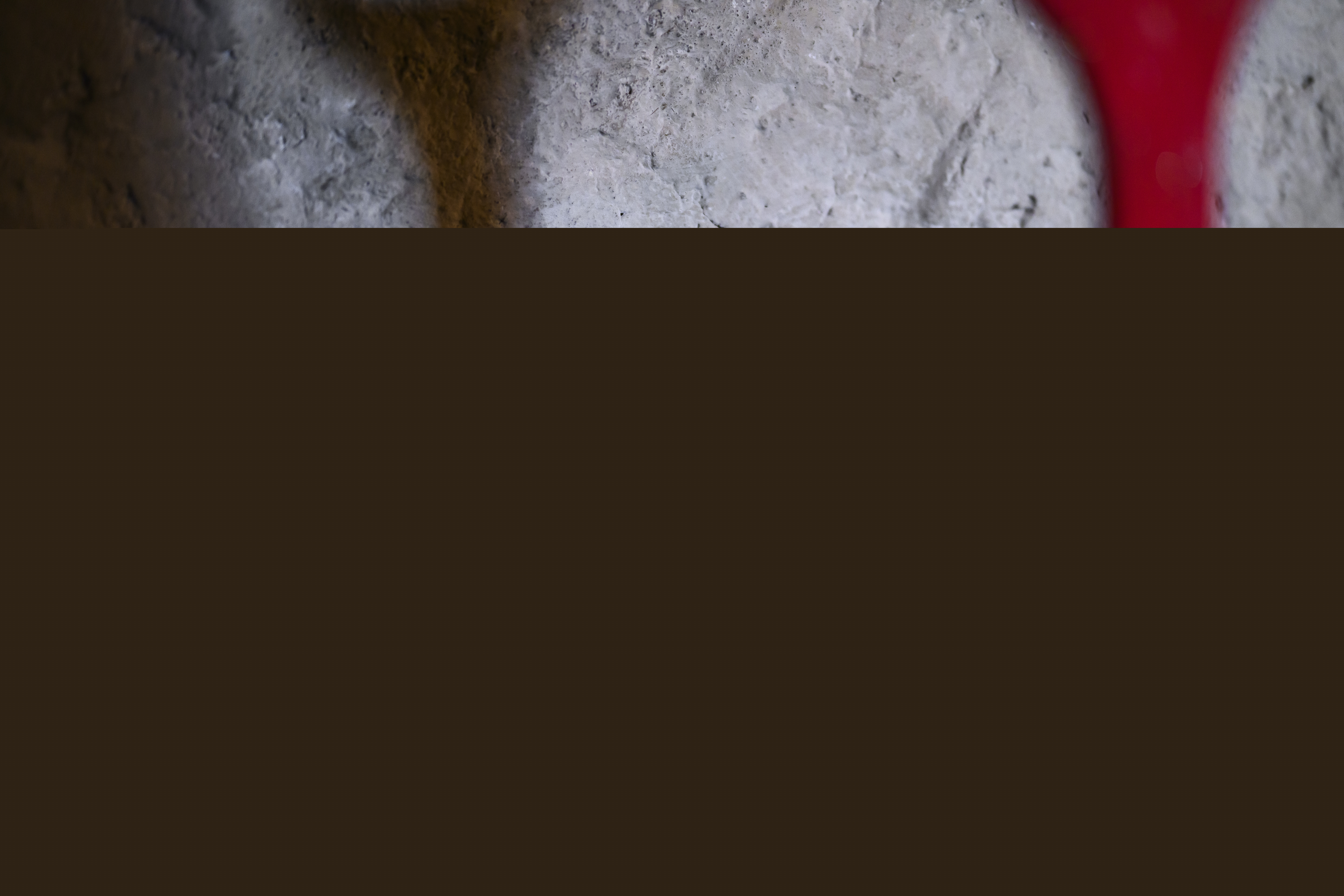 En skugga av ett kors på en stenvägg. Ett rött kors i förgrunden.