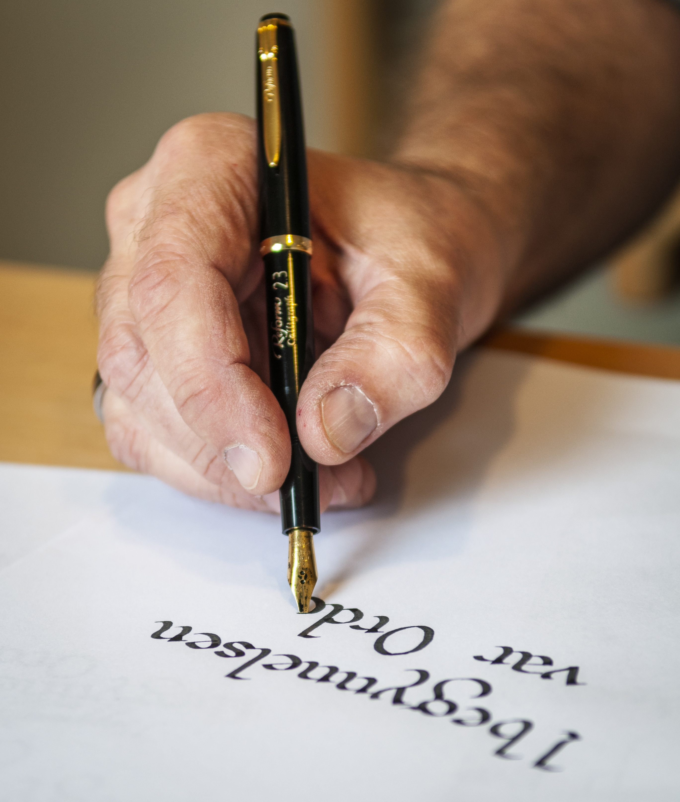 En kalligraf textar på ett vitt papper.