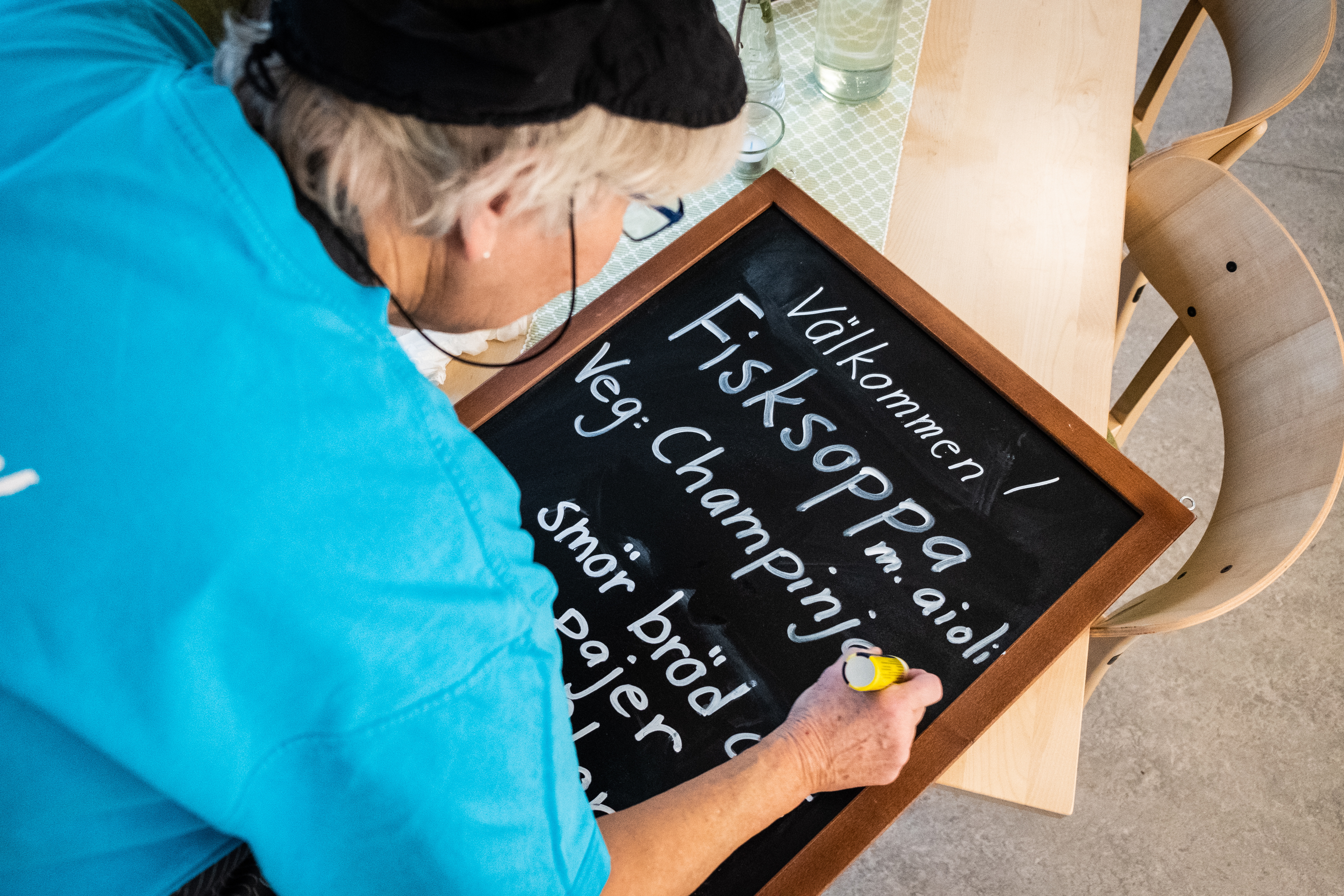En person skriver en meny på en griffeltavla.