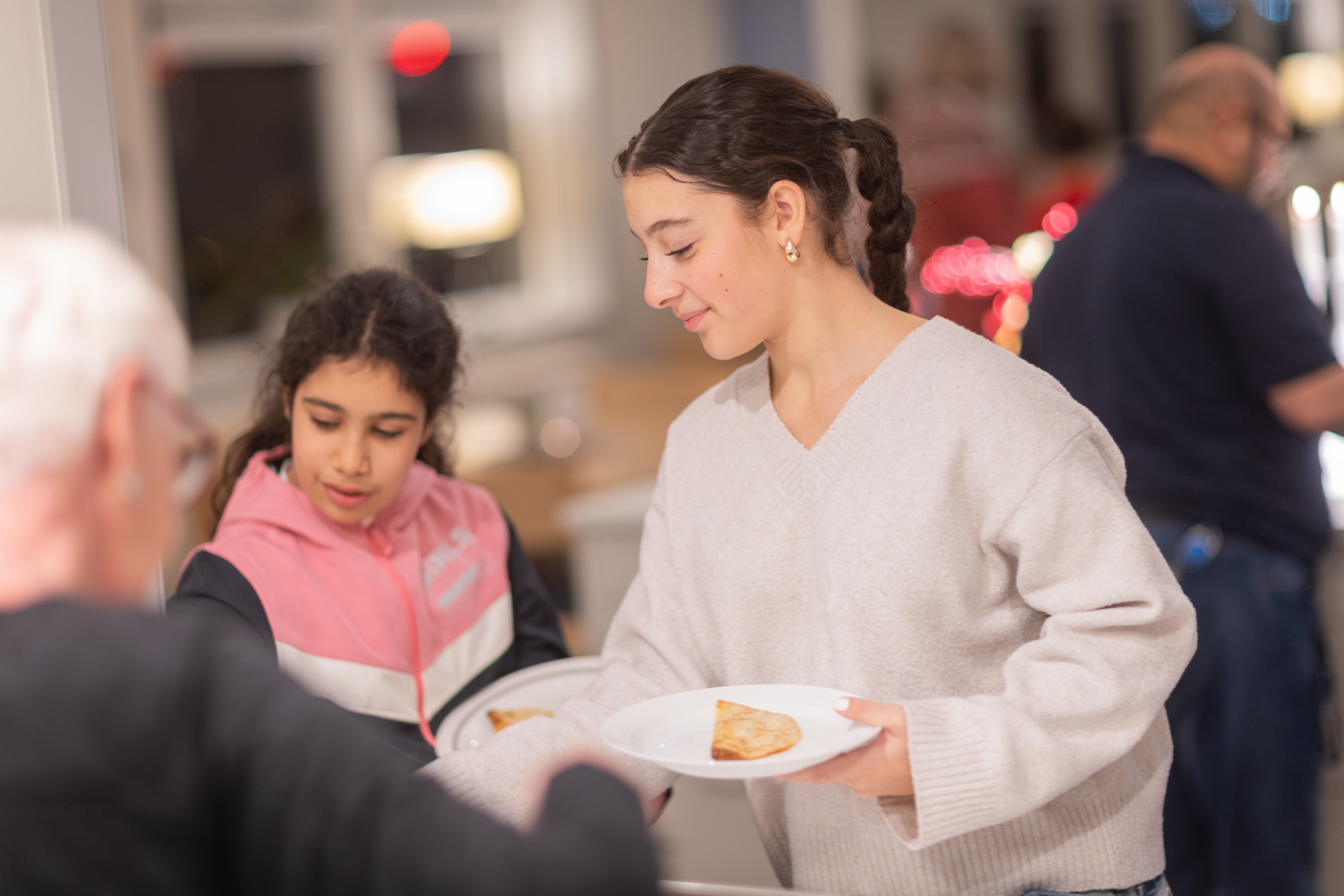Två tjejer får pannkakor i en matbespisning.
