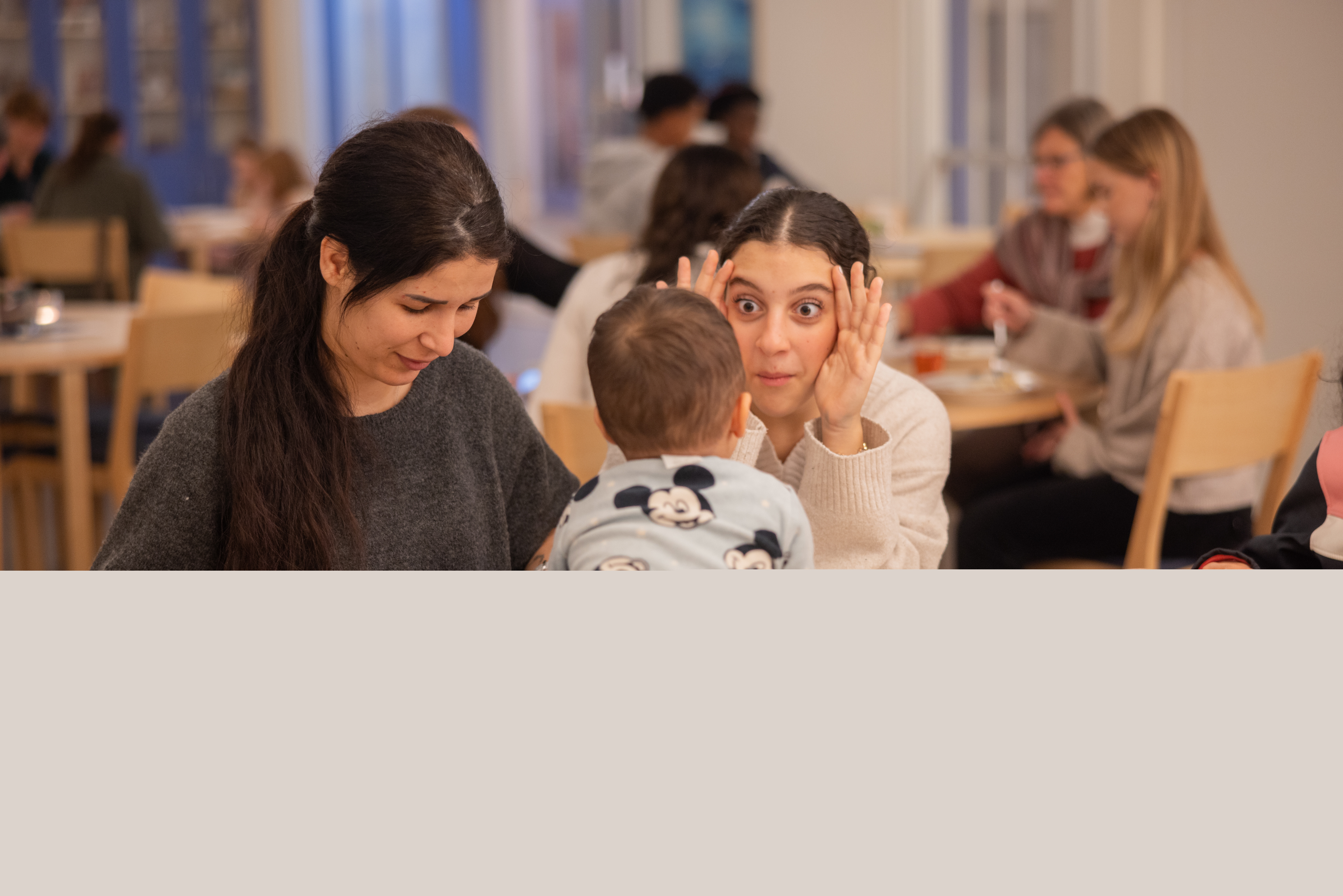 En tjej leker tittut med en liten pojke som sitter på ett bord.