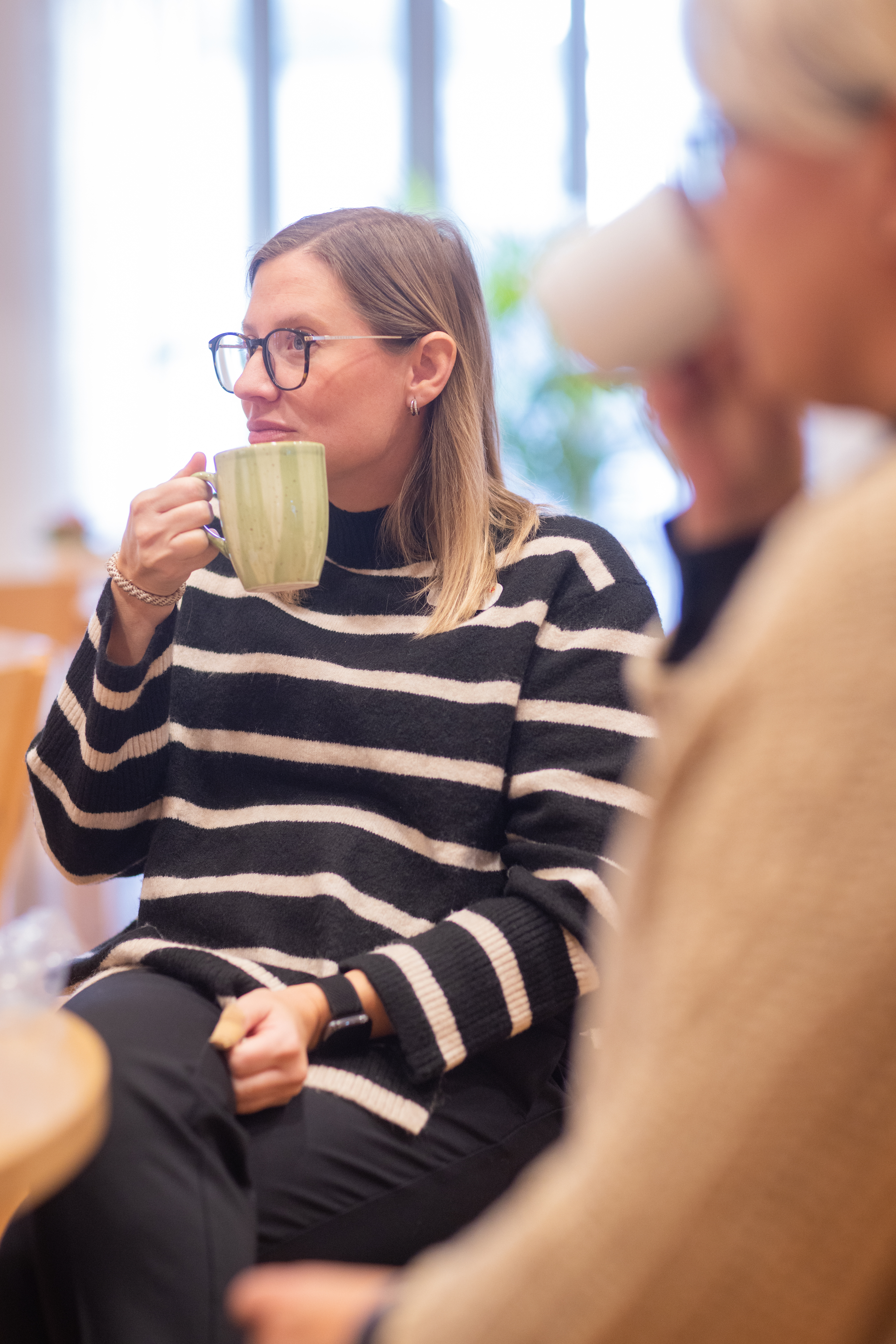 Två kvinnor sitter vid ett bord och fikar tillsammans.