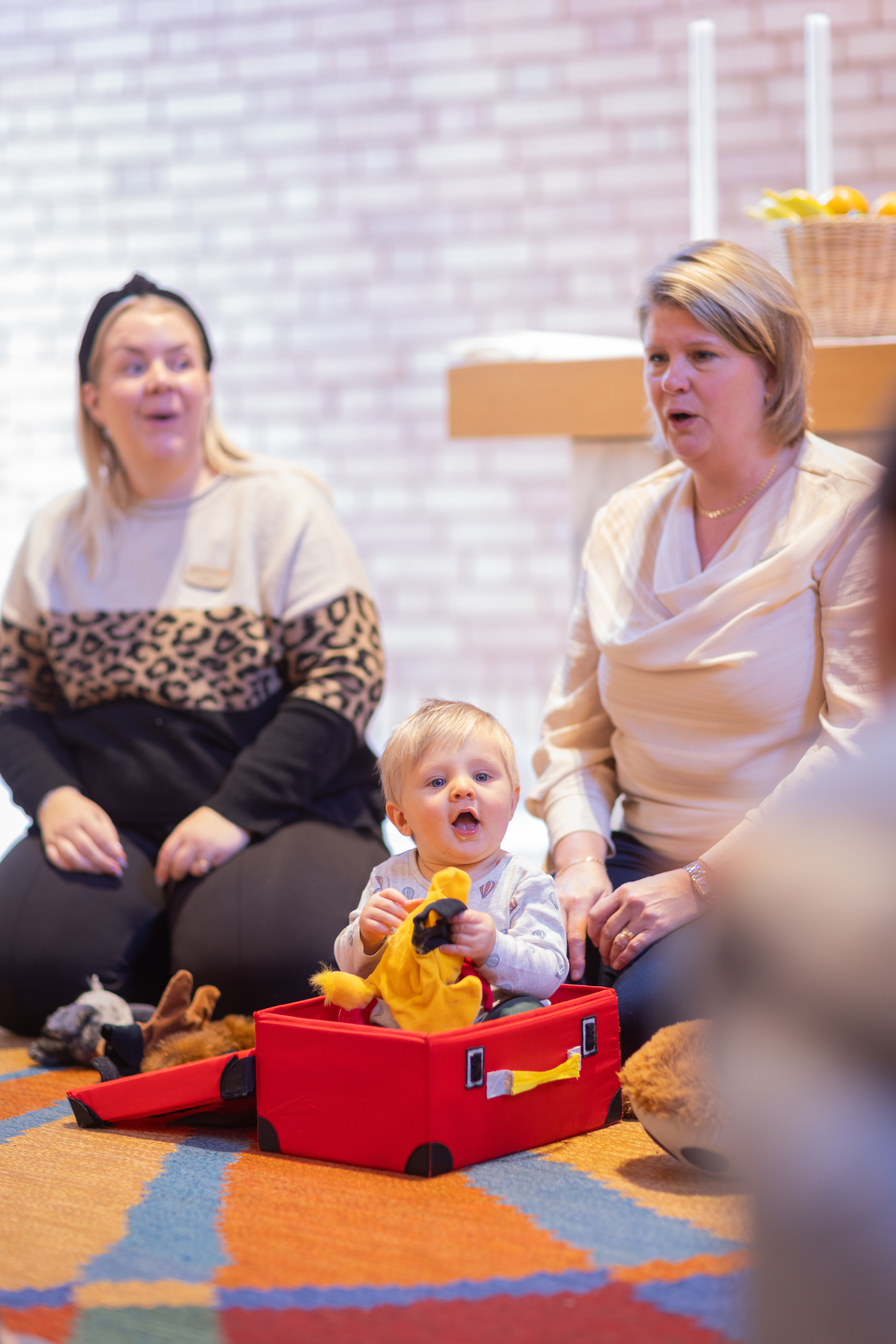 En öppen förskola där två kvinnor och ett barn deltar i en sångstund.