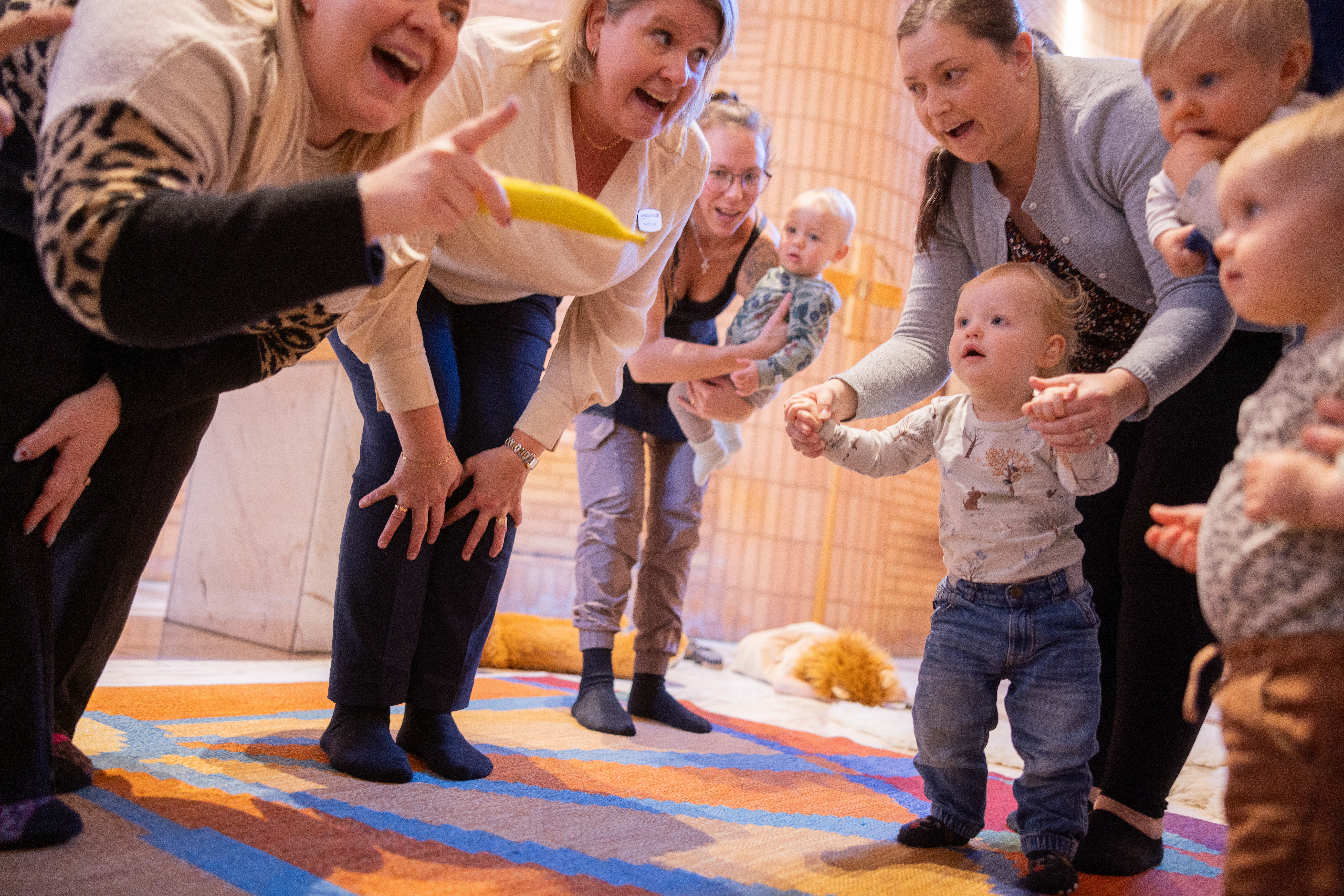 En närbild på kvinnor och barn på öppen förskola som leker och sjunger tillsammans.