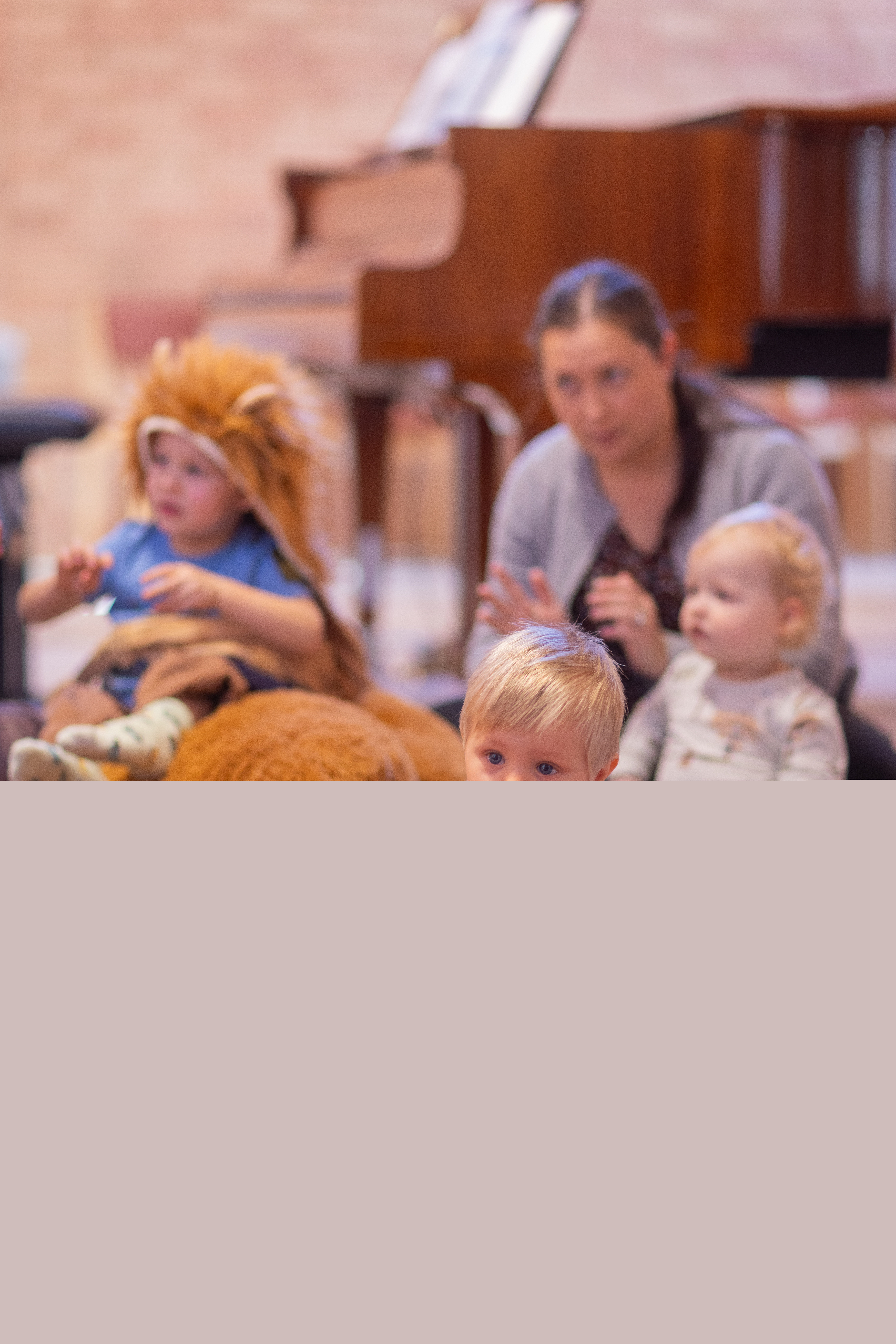 Lek på öppen förskola. Ett litet barn kryper på en matta i förgrunden.