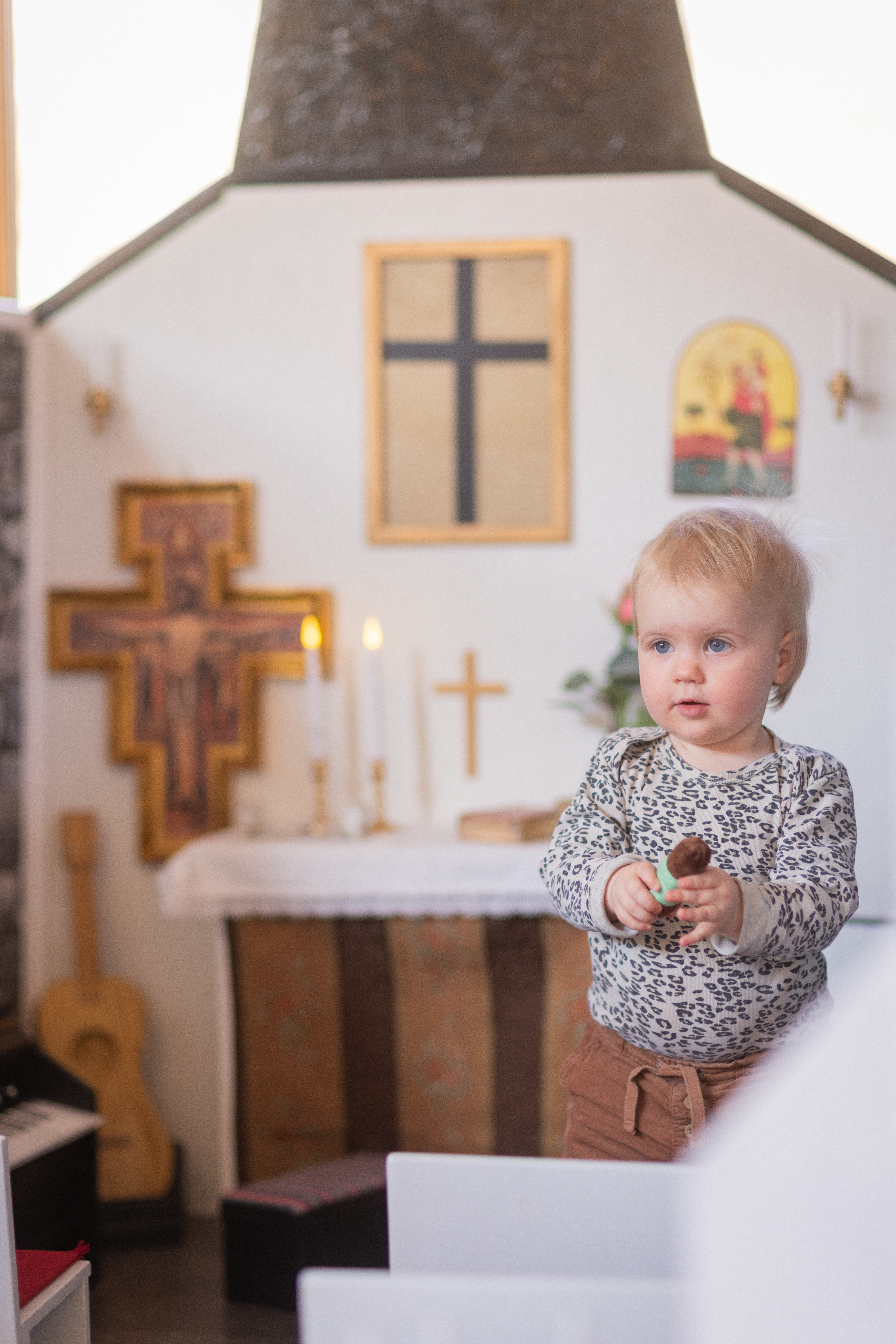 Ett litet barn står inne i en miniatyr-kyrka.