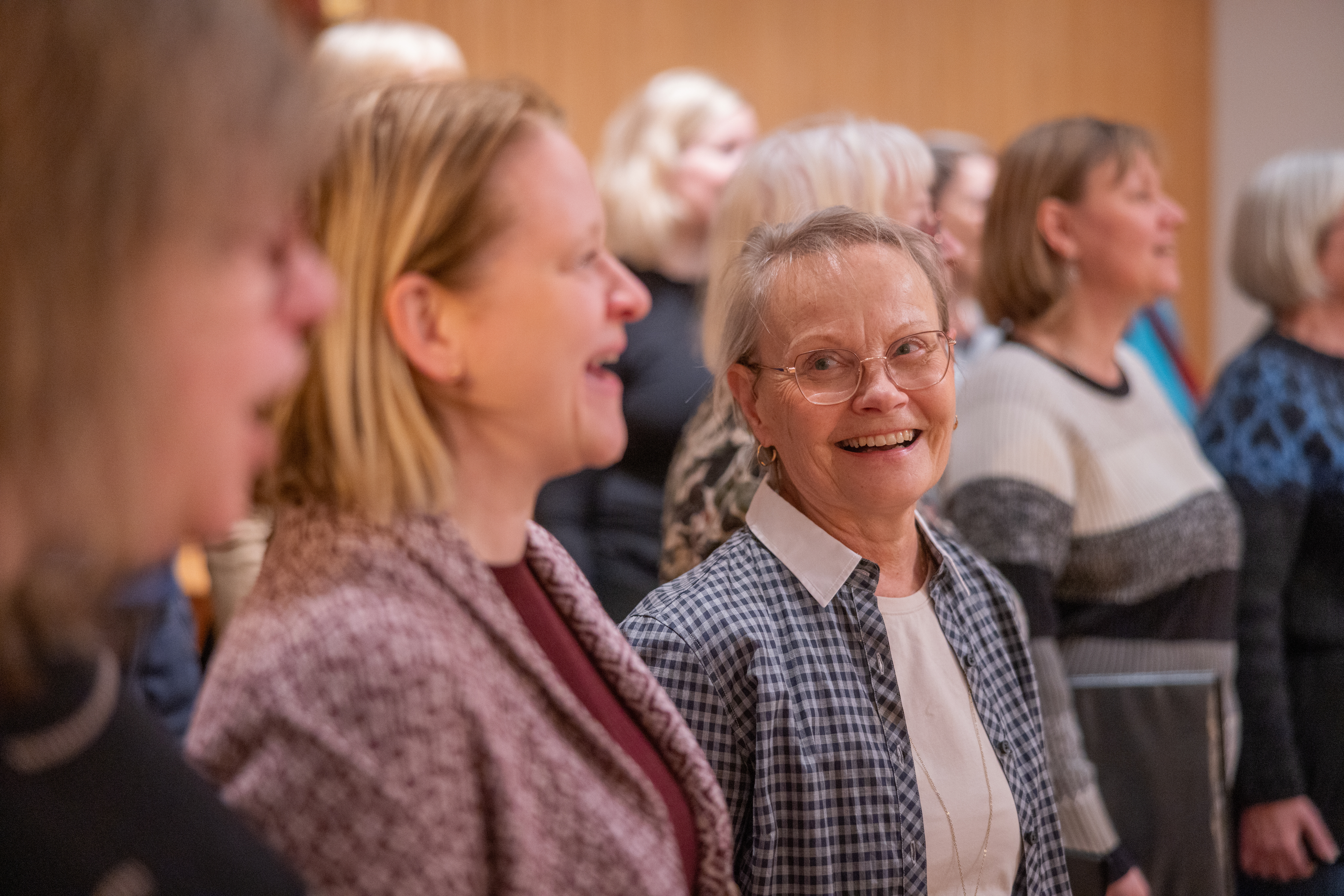 Närbild på leende kvinnor som sjunger i en kör.