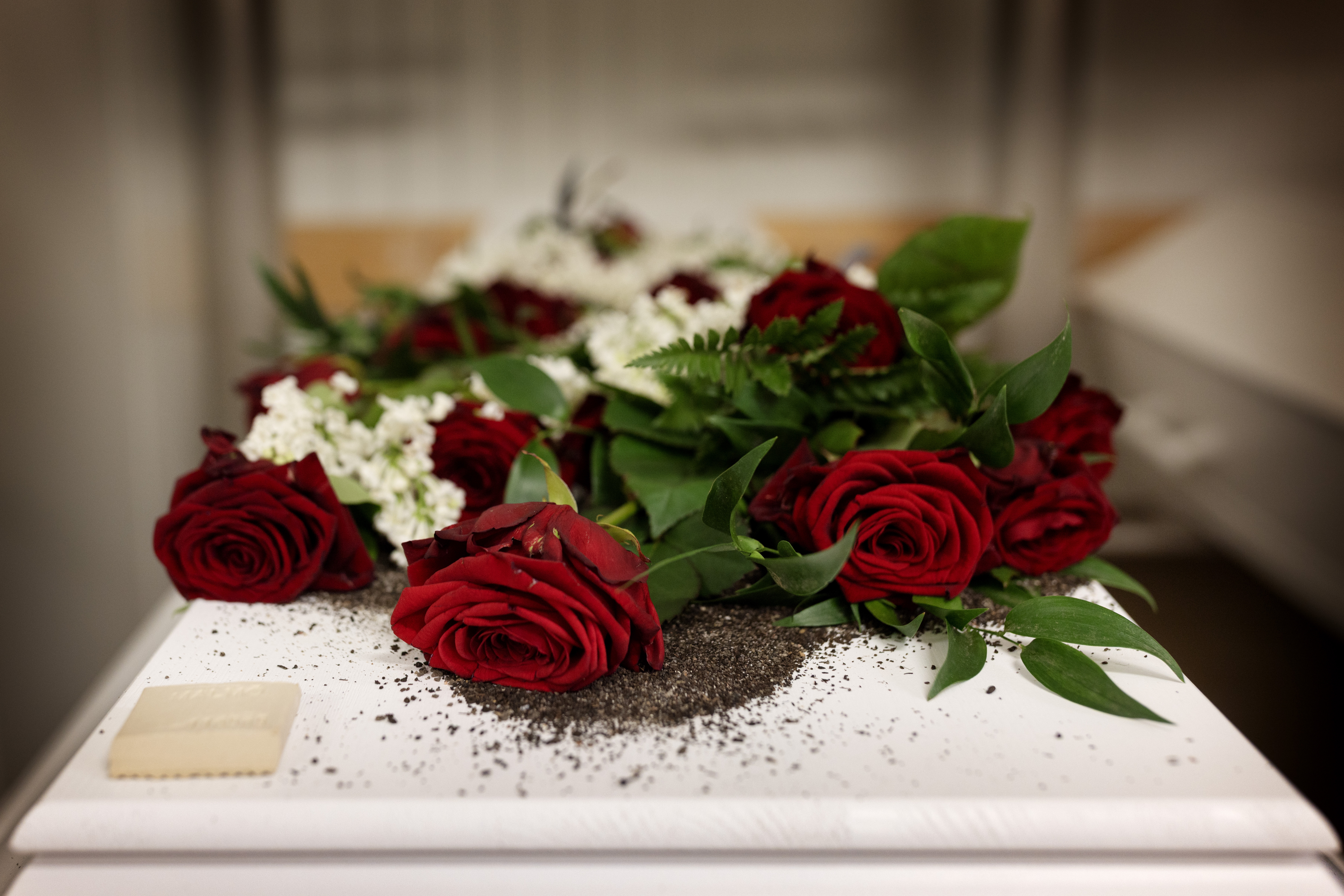 Närbild på en blombukett med röda och vita blommor på en vit kista.