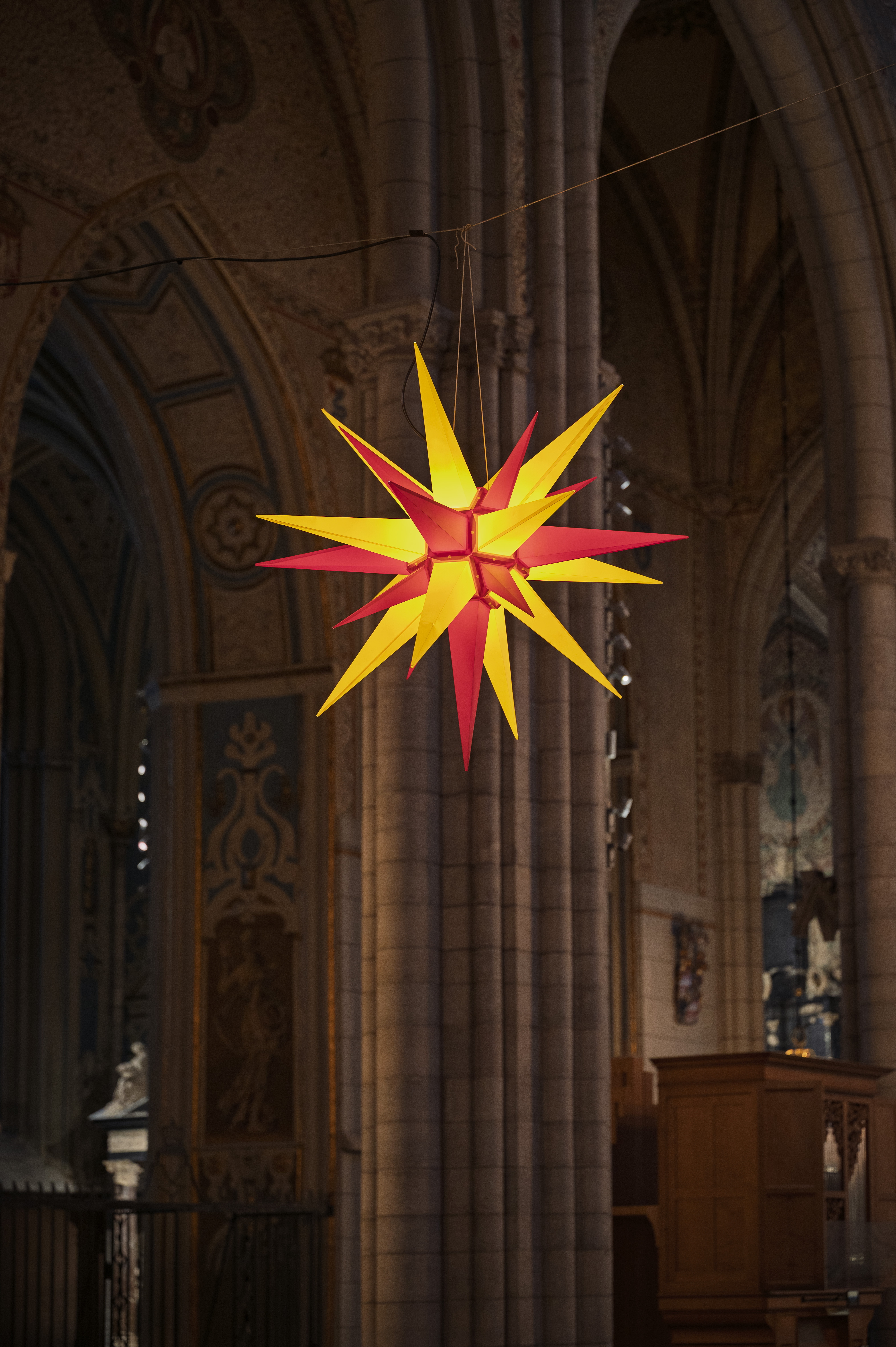 En tänd julstjärna i gult och rött hänger i Uppsala domkyrka.