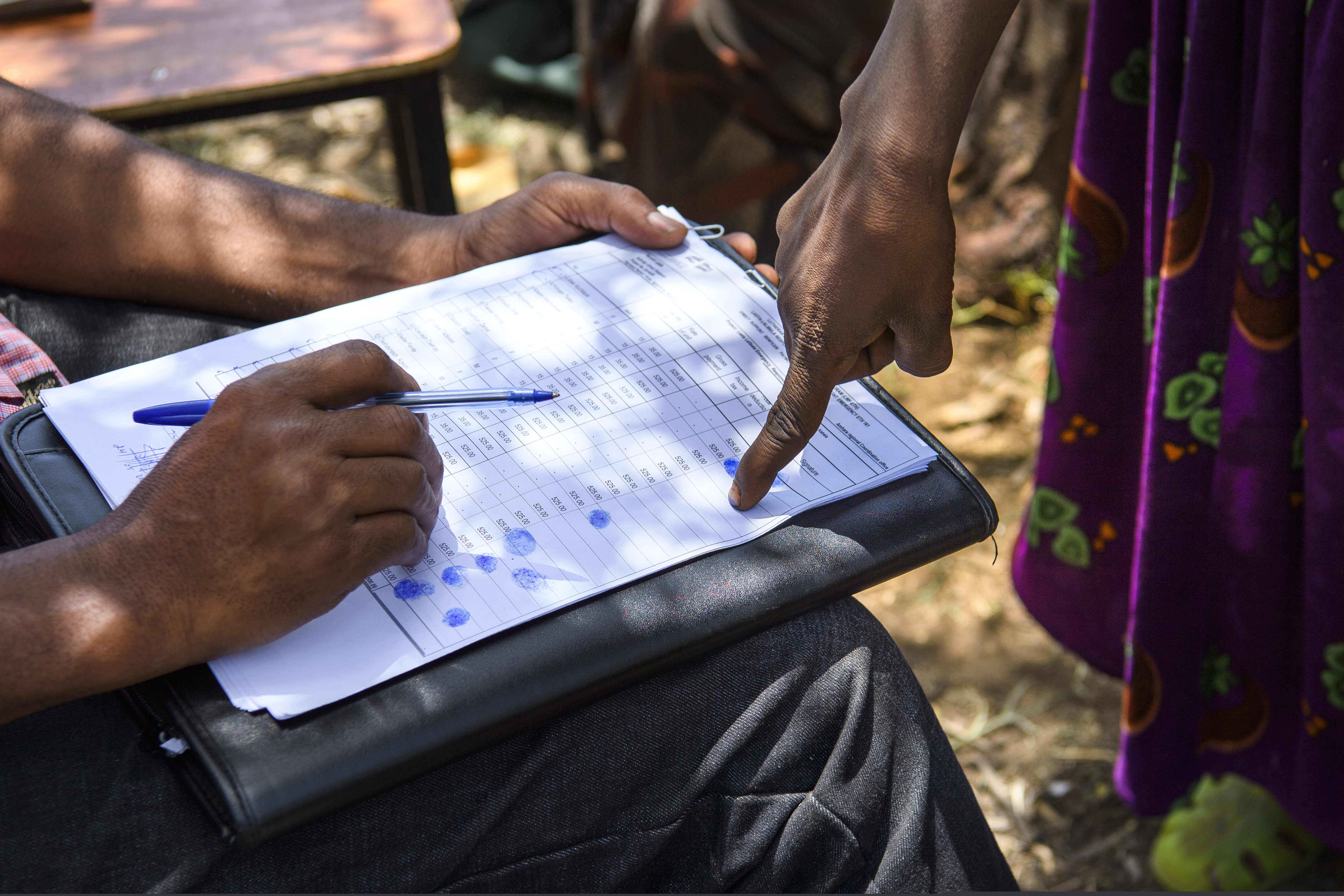 Kvinna sätter sitt fingeravtryck på ett papper nr hon kvitterar ut sin lön.