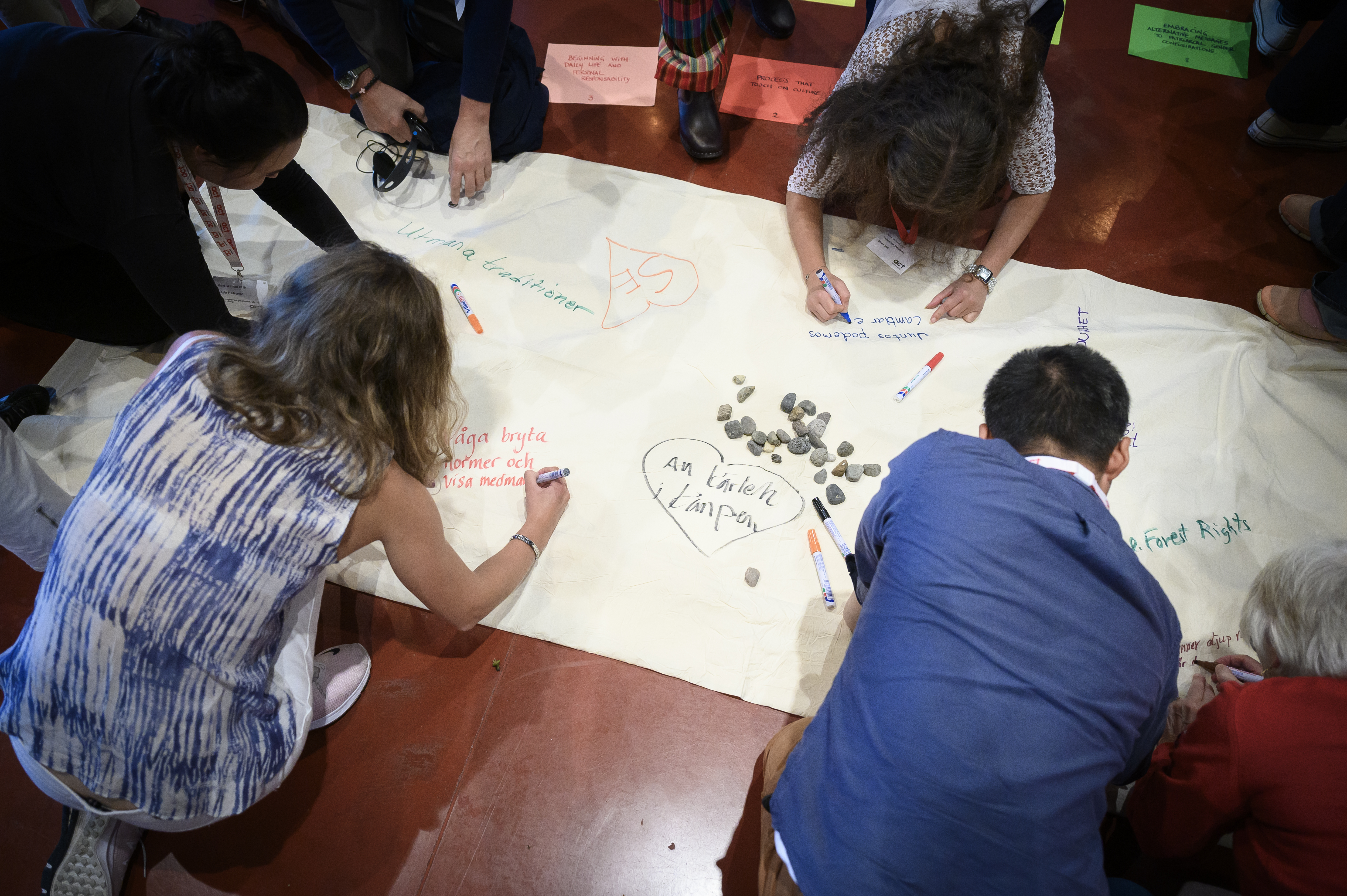 Workshop. Några personer skriver på en stor duk på golvet.