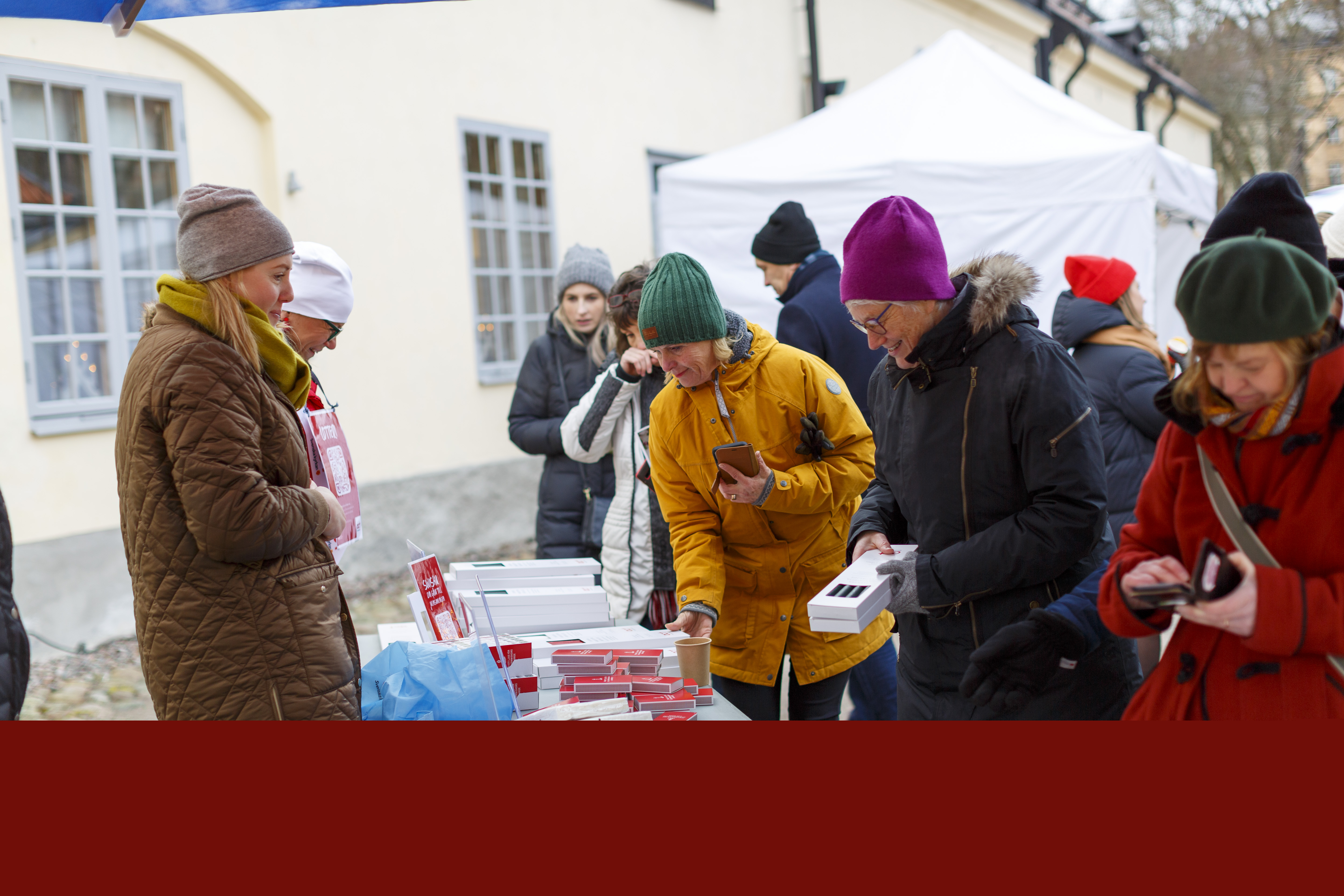 Arbetare från Act Svenska kyrkan står utomhus och säljer ljus och tändstickor.