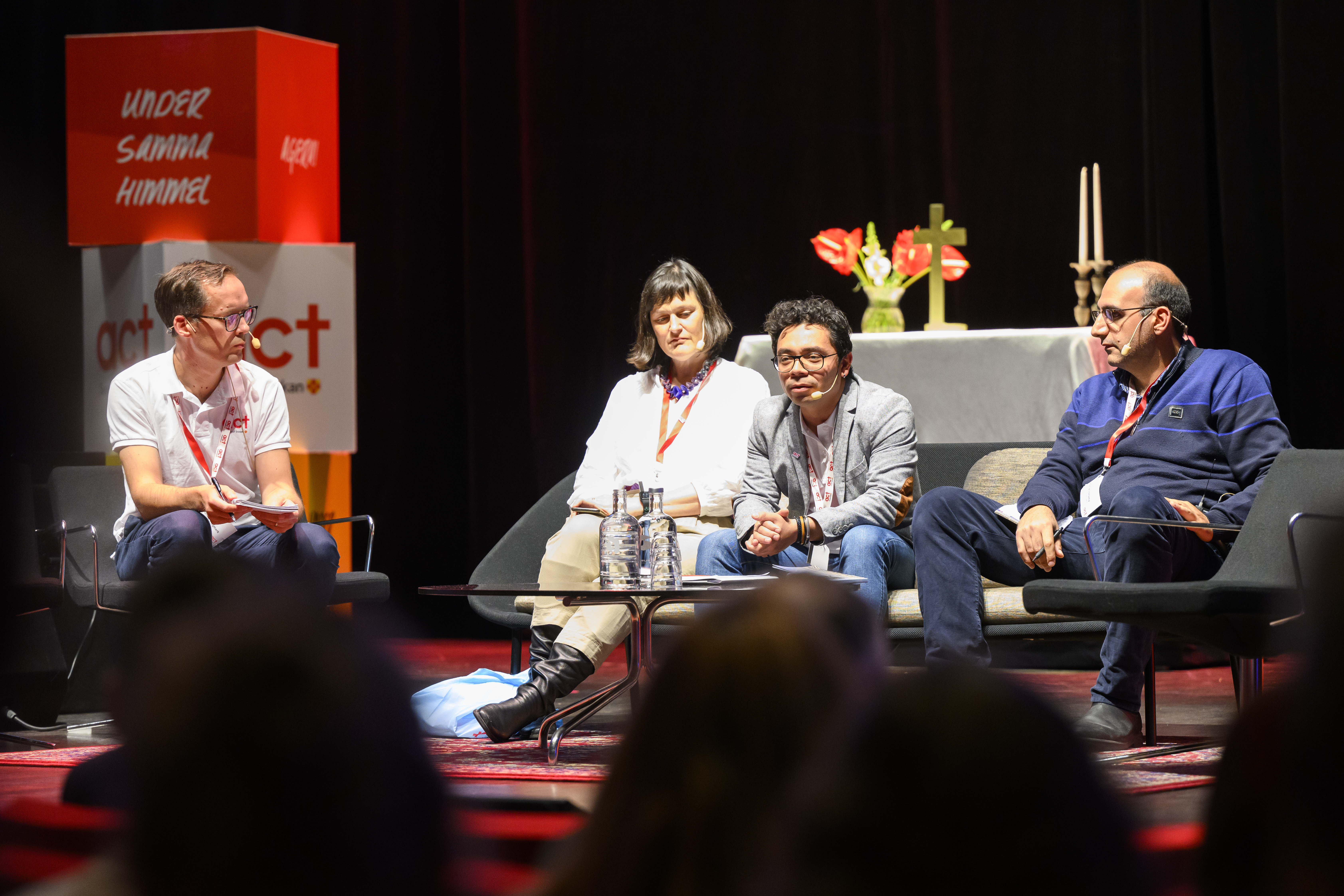 Panelsamtal. Man i fotölj samtalar med tre gäster. 