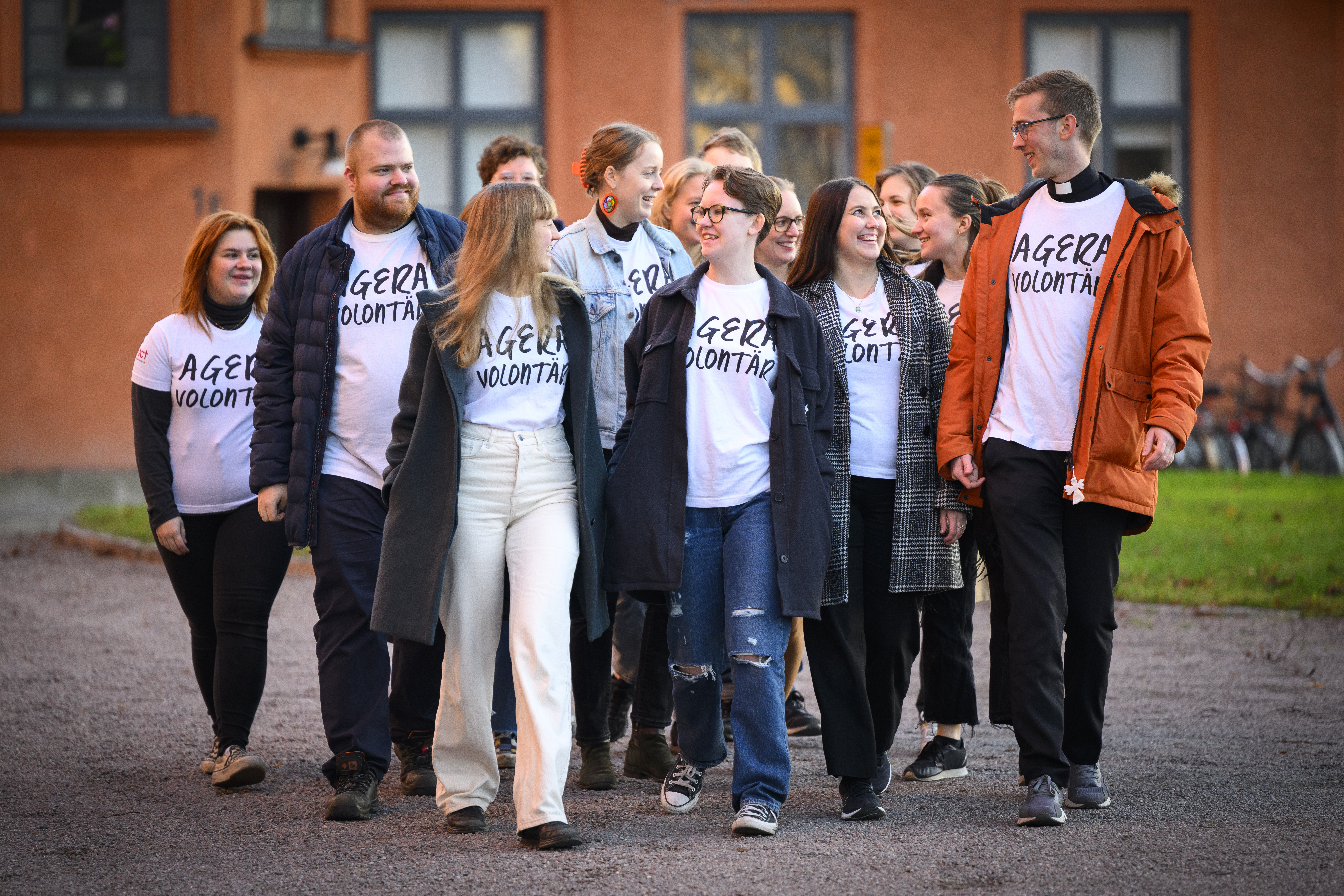 En grupp glada personer går tätt ihop och pratar med personen bredvid. 
