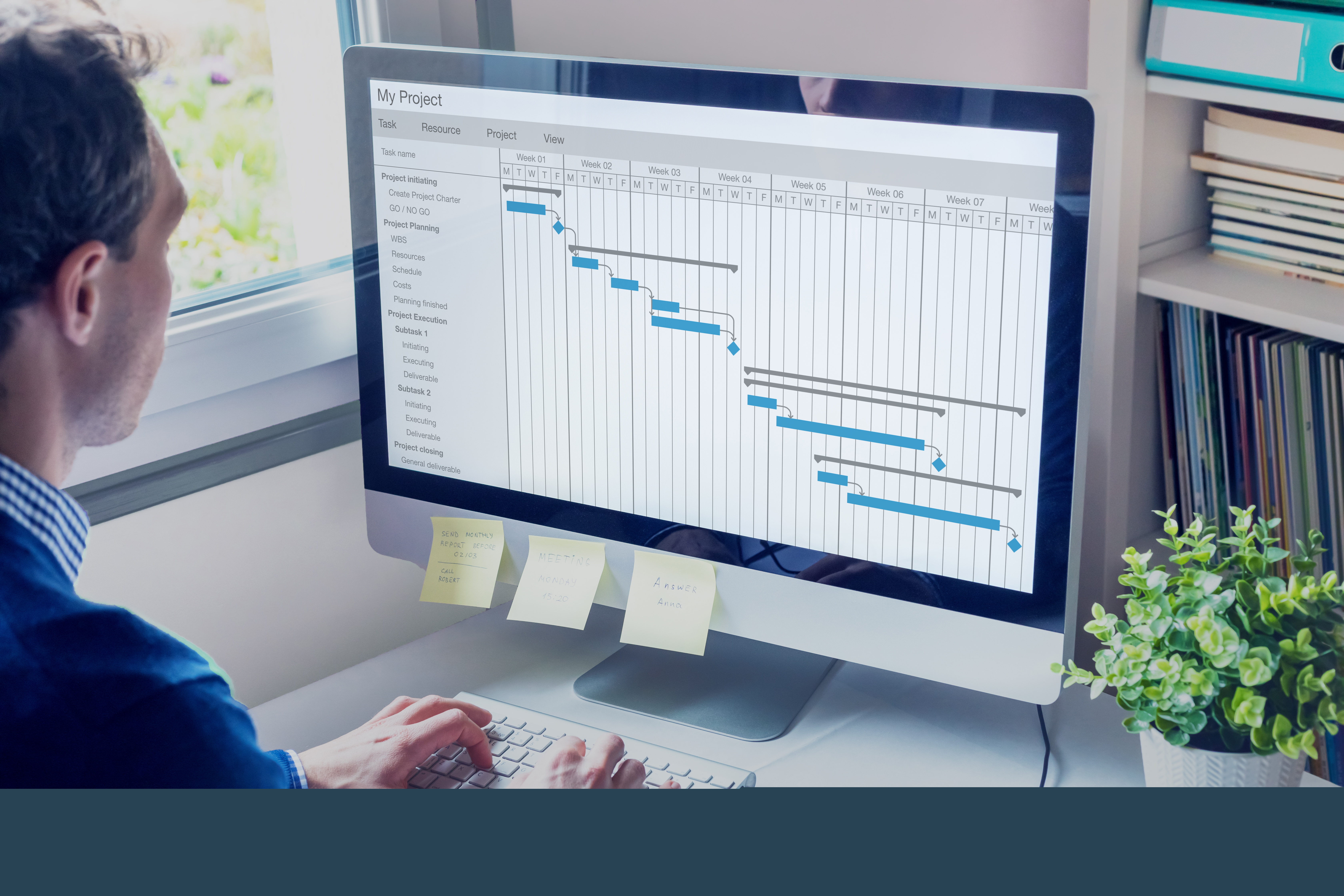 En person sitter vid sin dator. På skärmen syns ett gantt-schema för ett projekt.