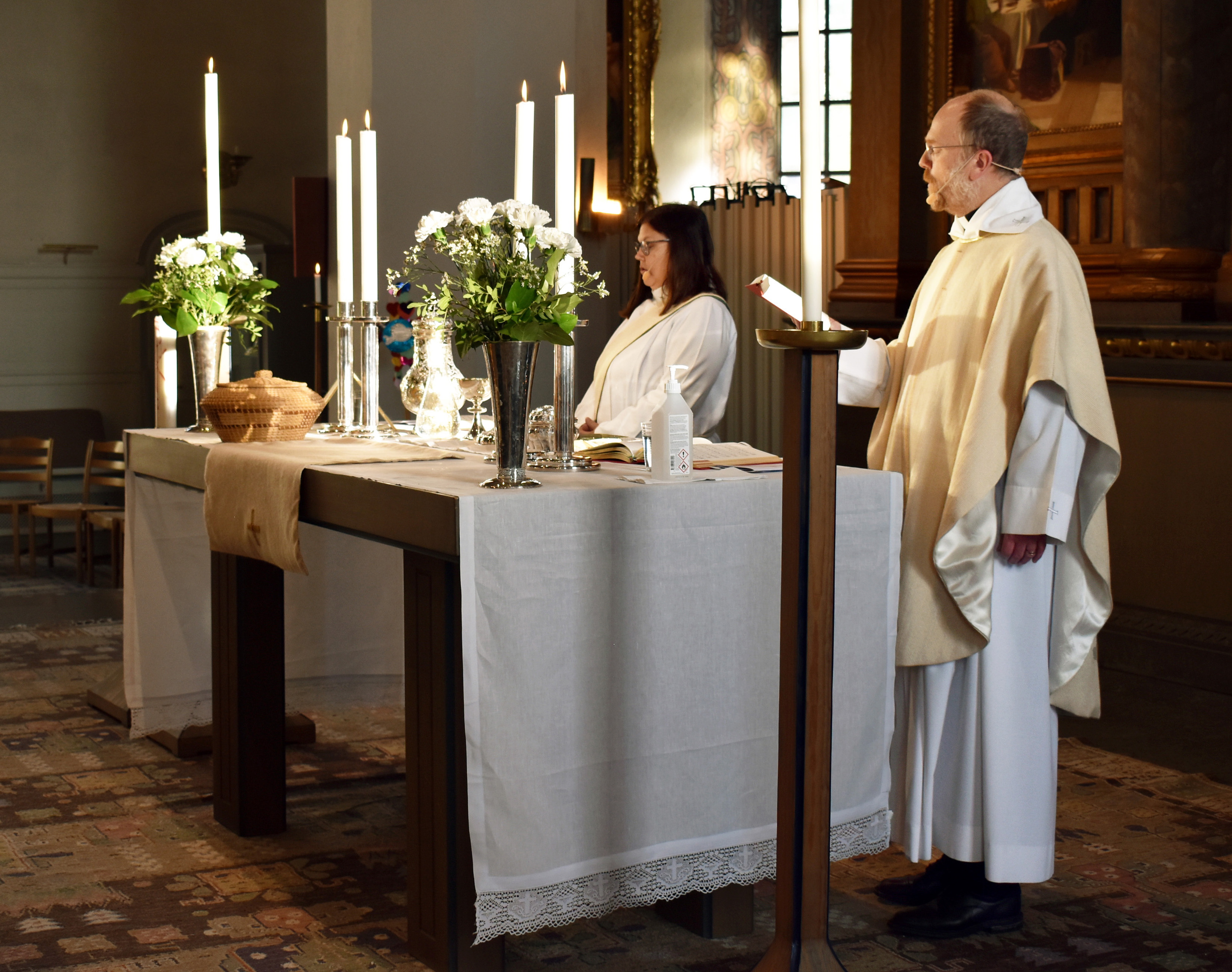 Präst och diakon vid altare dukat för nattvard.