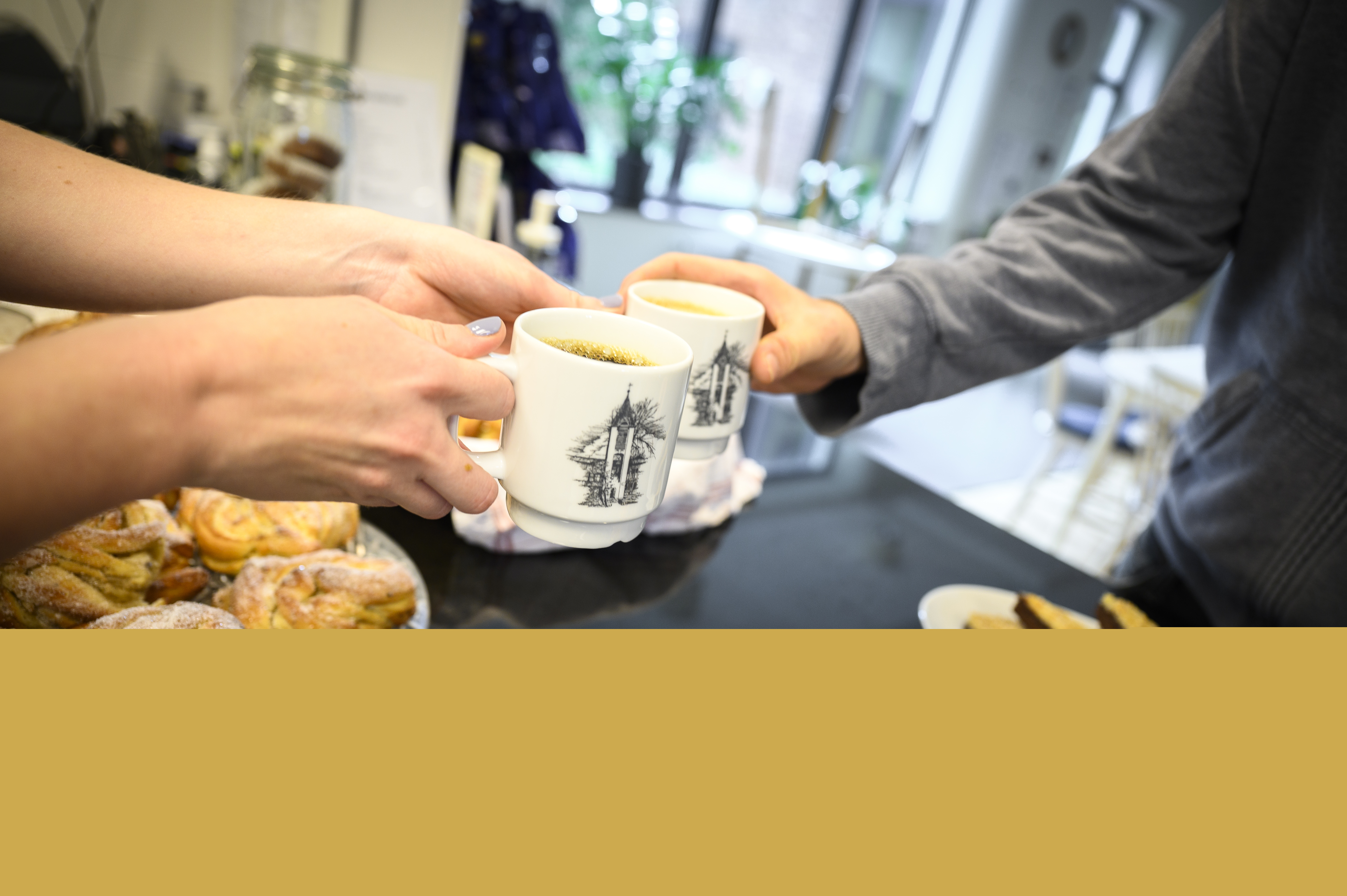 Någon räcker över en kopp kaffe över ett fikabord.